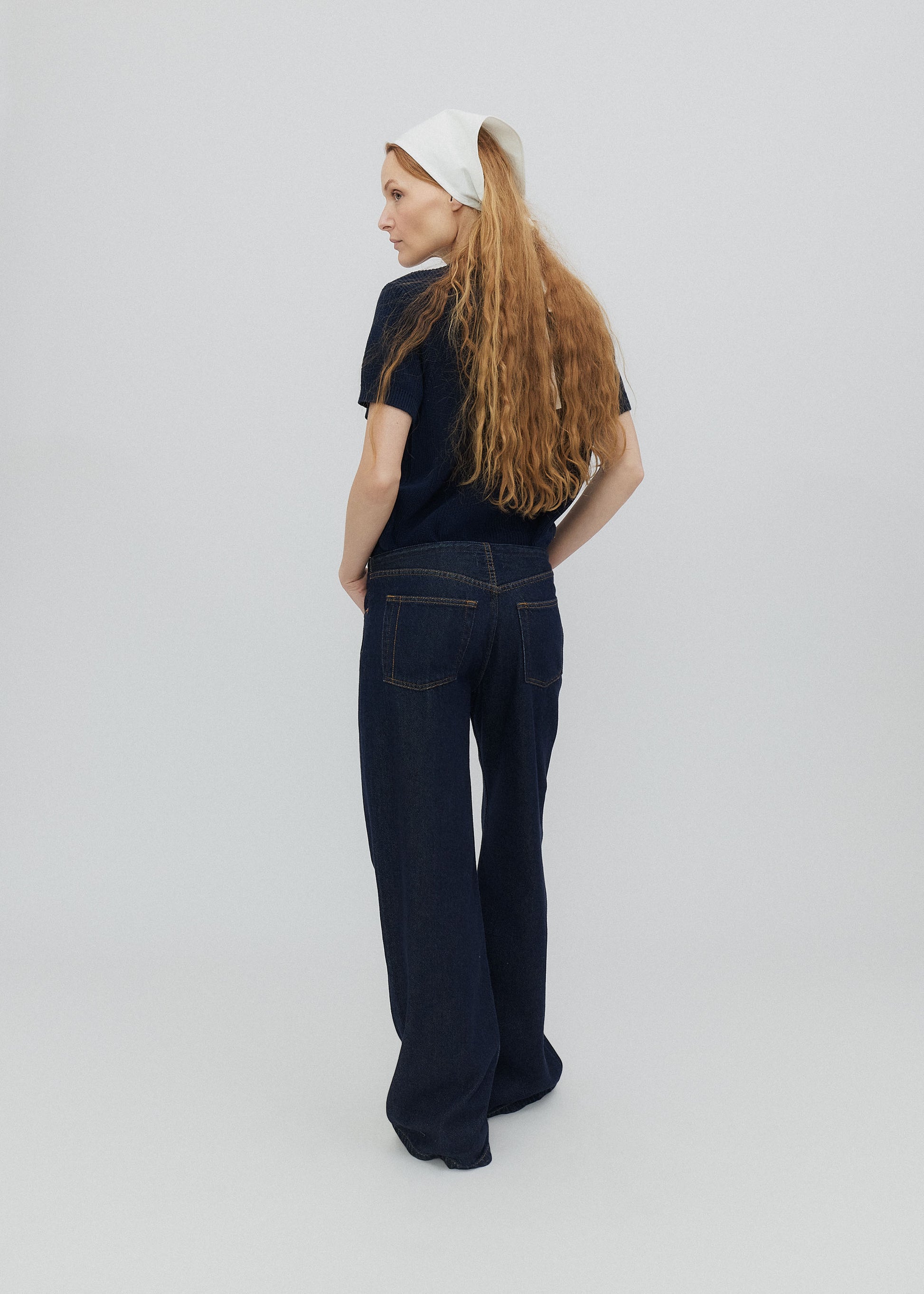 Person wearing a black outfit with a white headband on a plain background