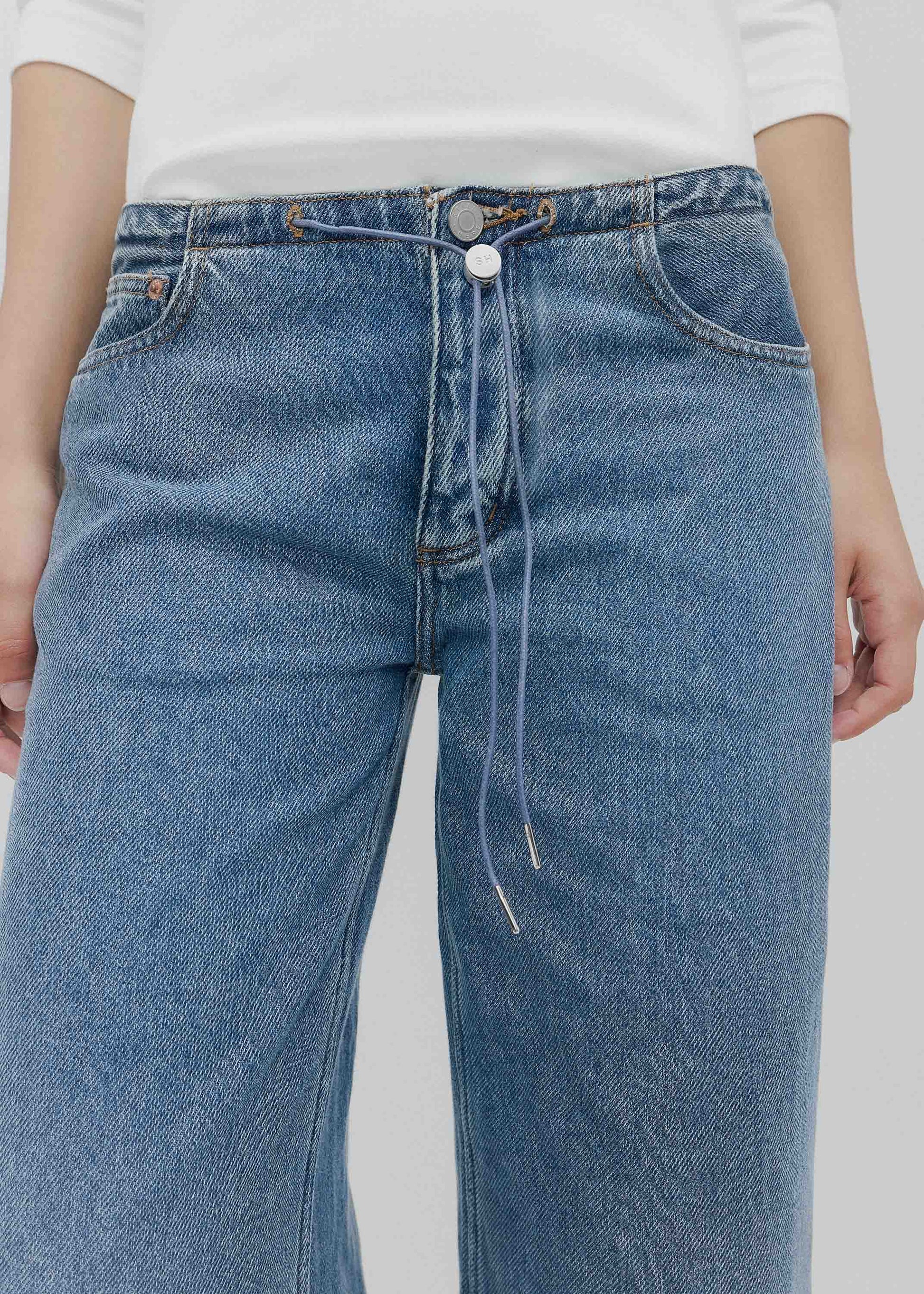 Blue jeans worn by a person on a plain background