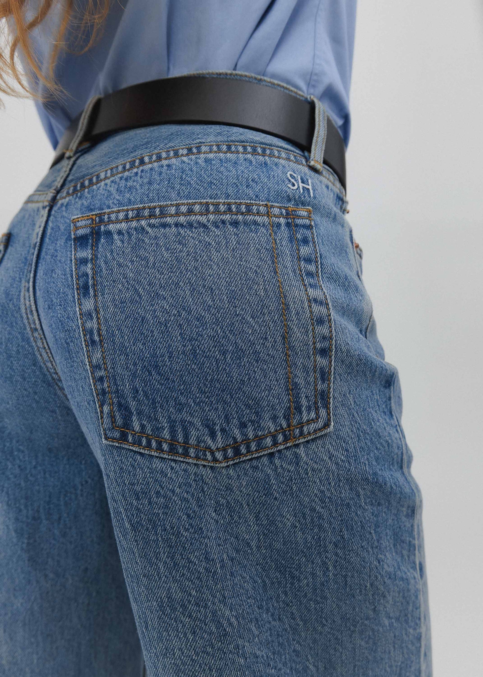 Close-up of blue jeans with a black belt on a plain background