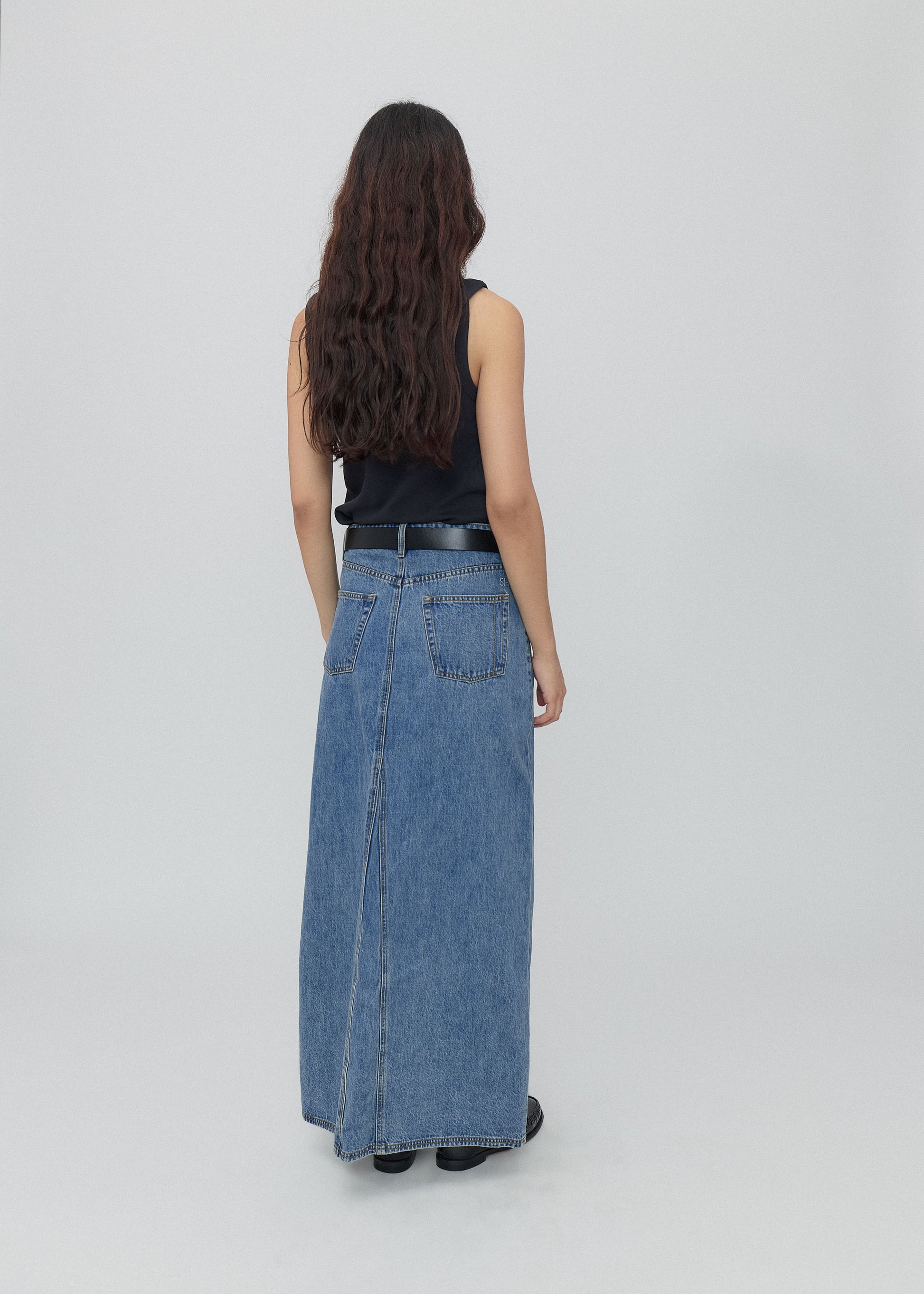 Woman wearing a long blue denim skirt on a white background