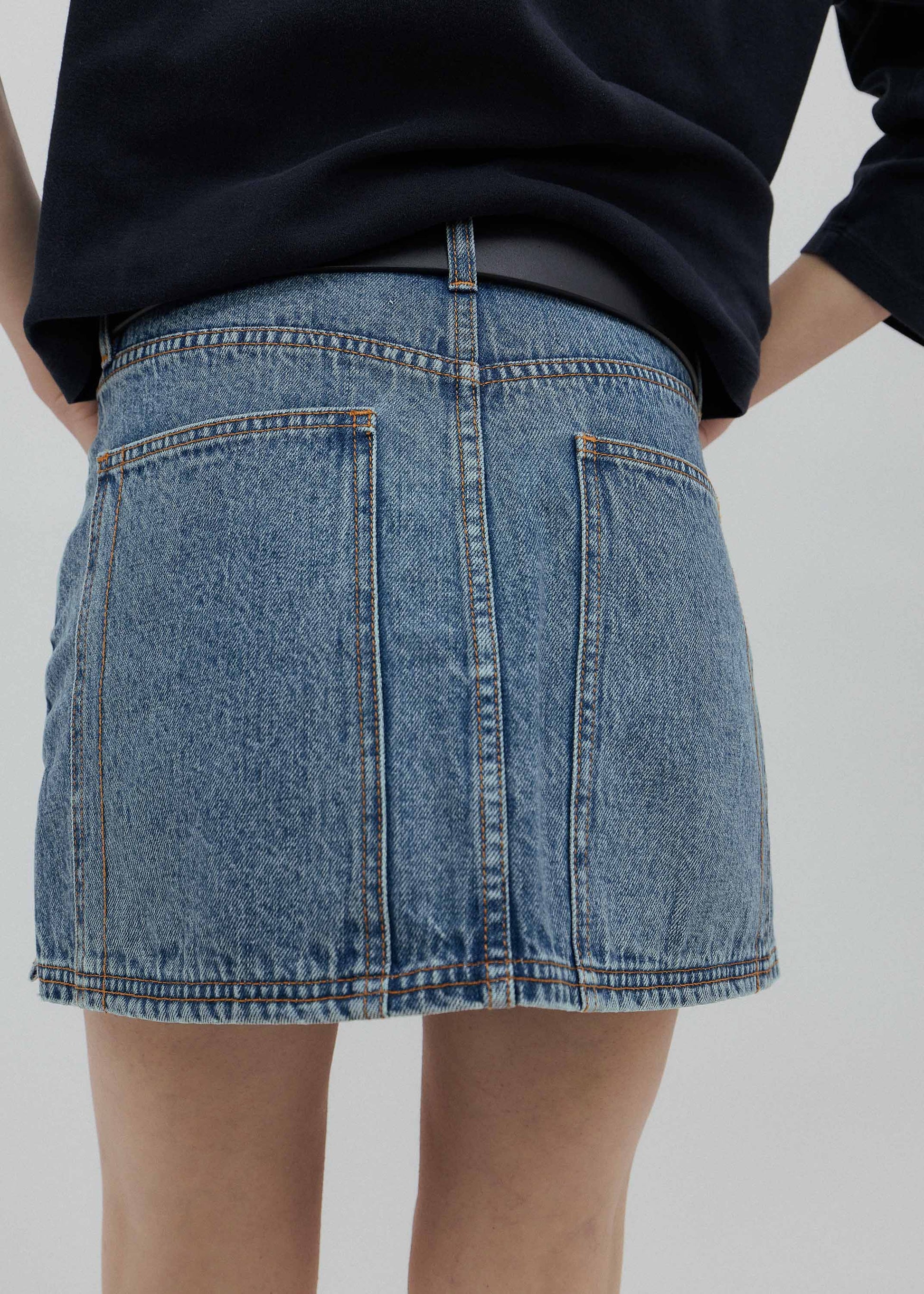 Person wearing a blue denim skirt on a plain background