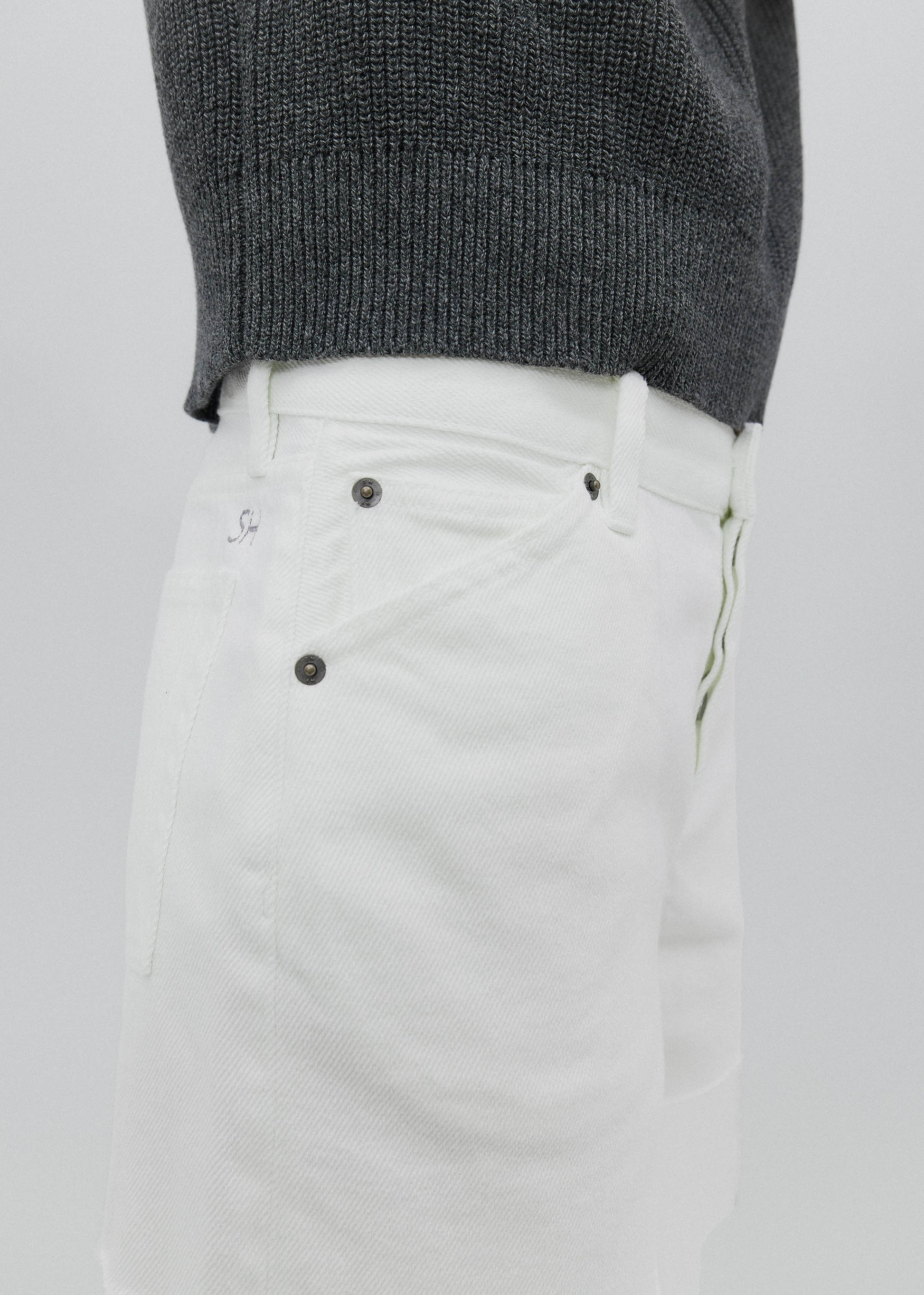 White pants with a gray sweater on a light gray background