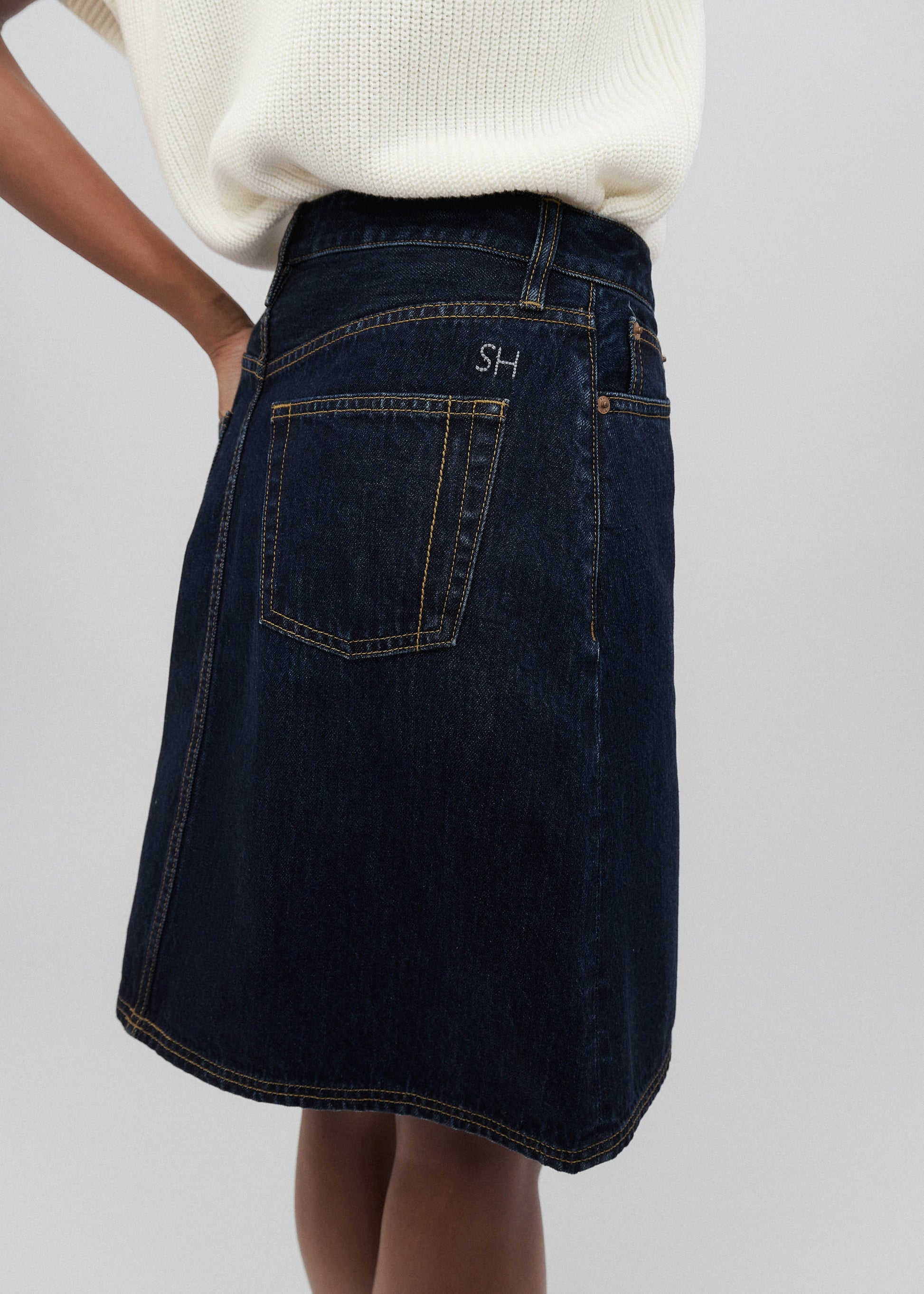 Dark denim skirt with a brand logo on a plain background