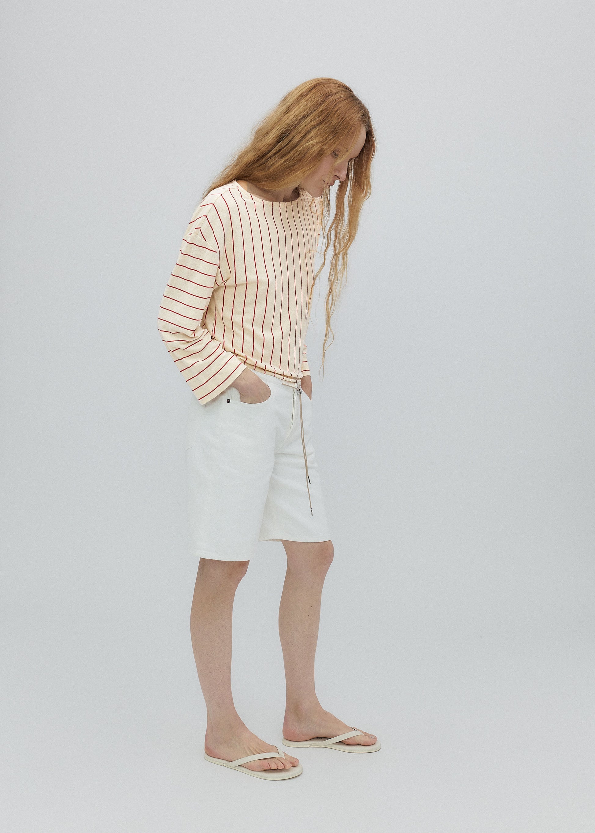 Person wearing a striped sweater and white skirt on a plain background