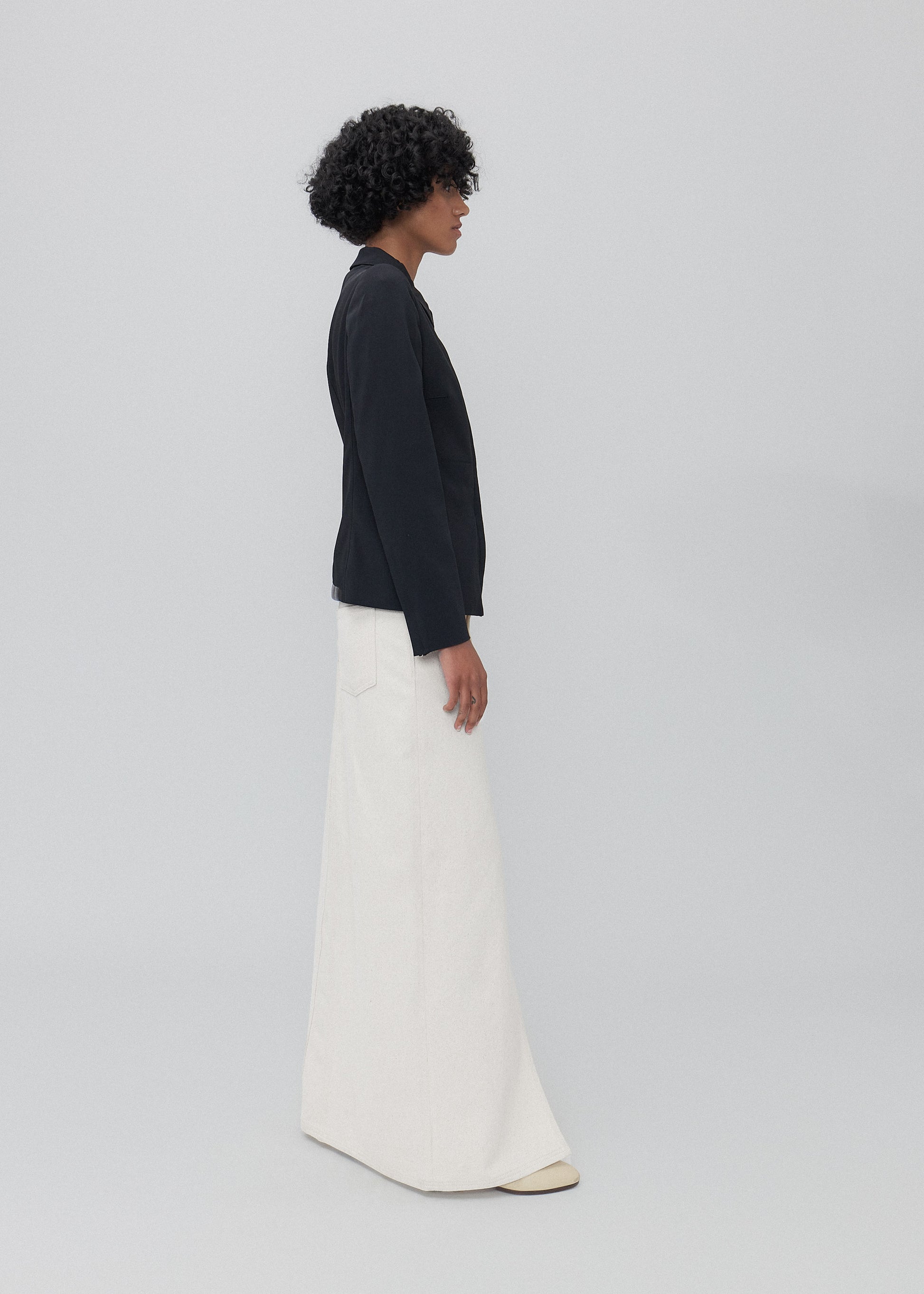 Person wearing a black top and white pants on a light gray background