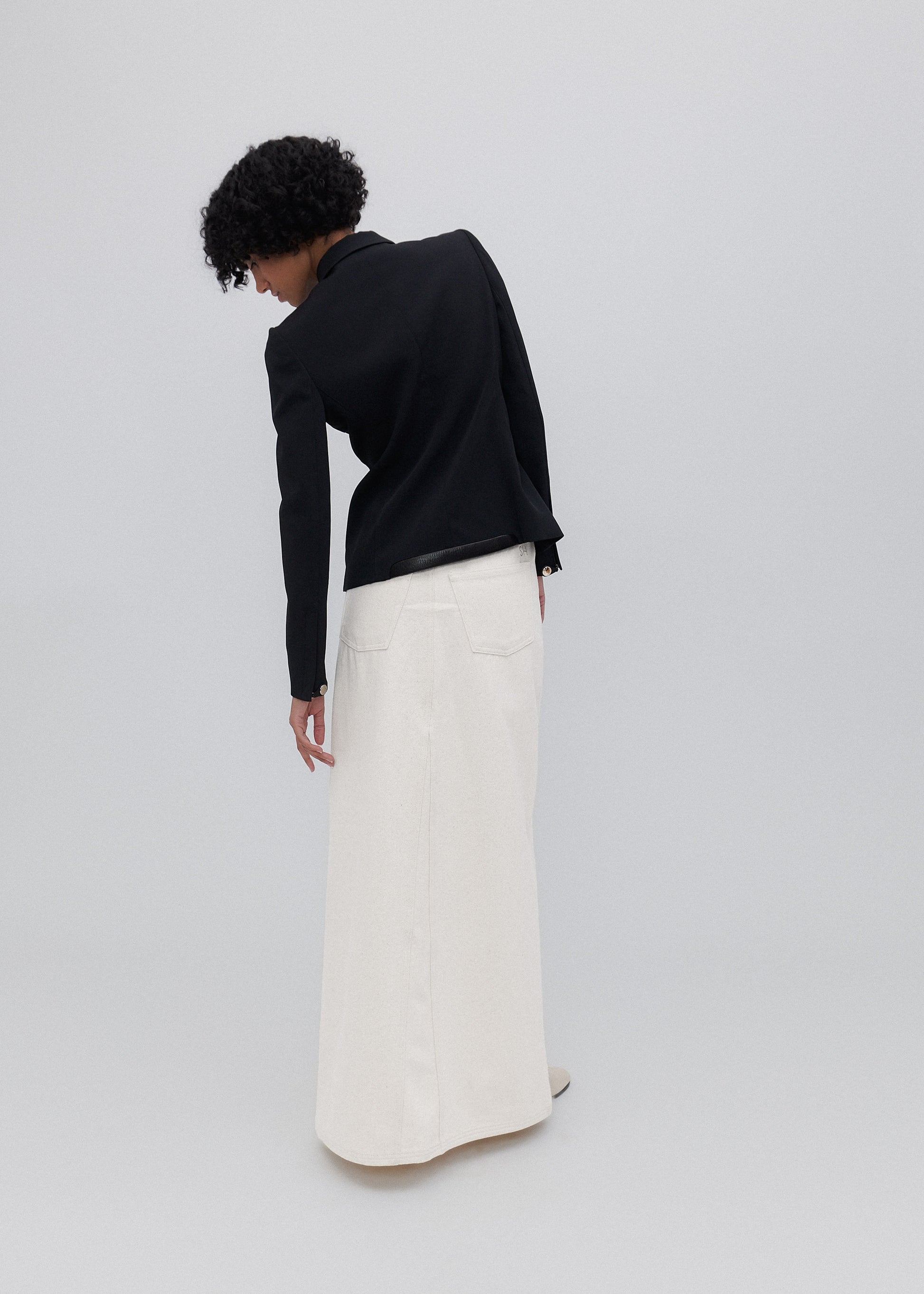 Person wearing a black sweater and white pants on a light gray background