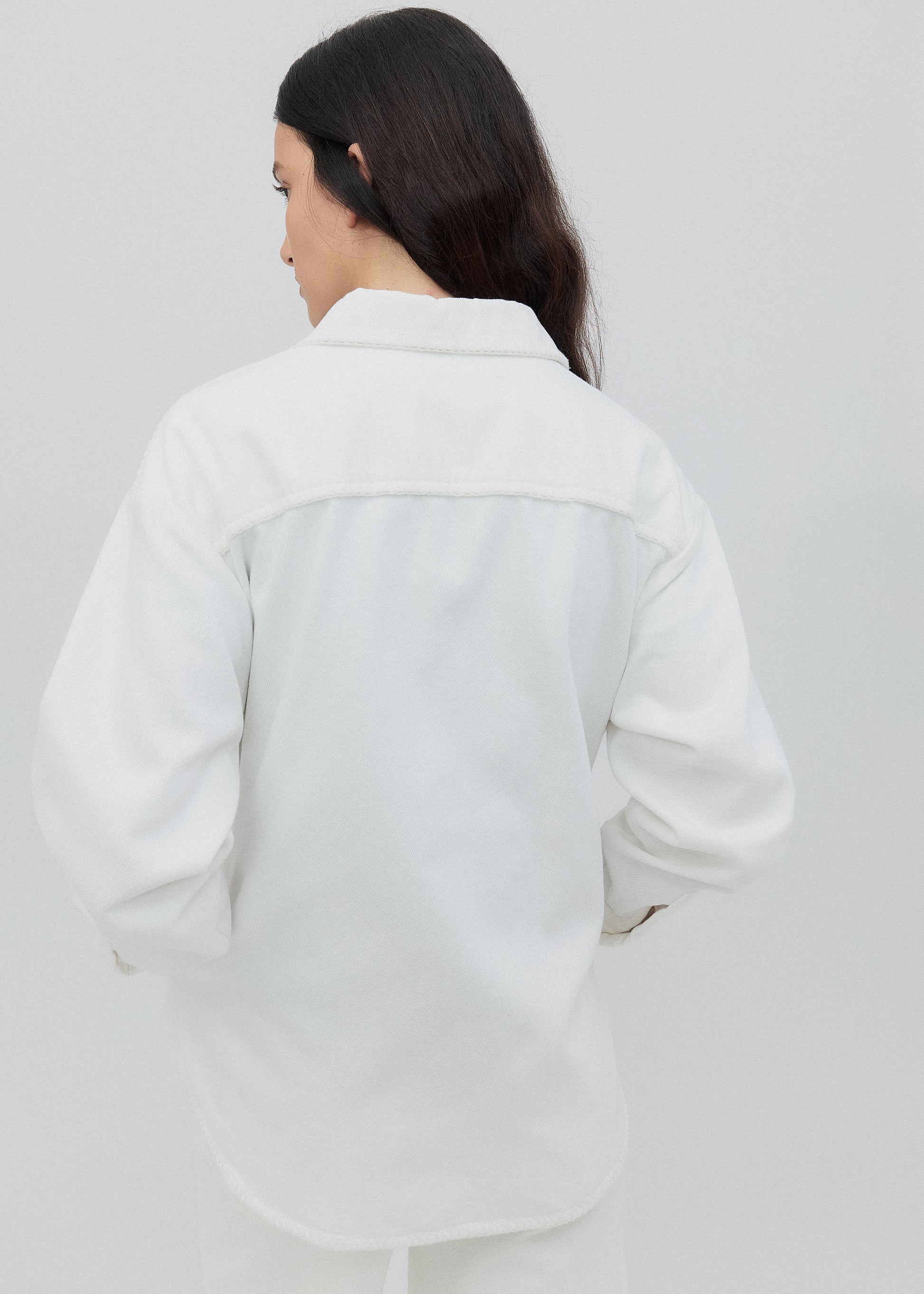 Person wearing a light-colored jacket on a plain background