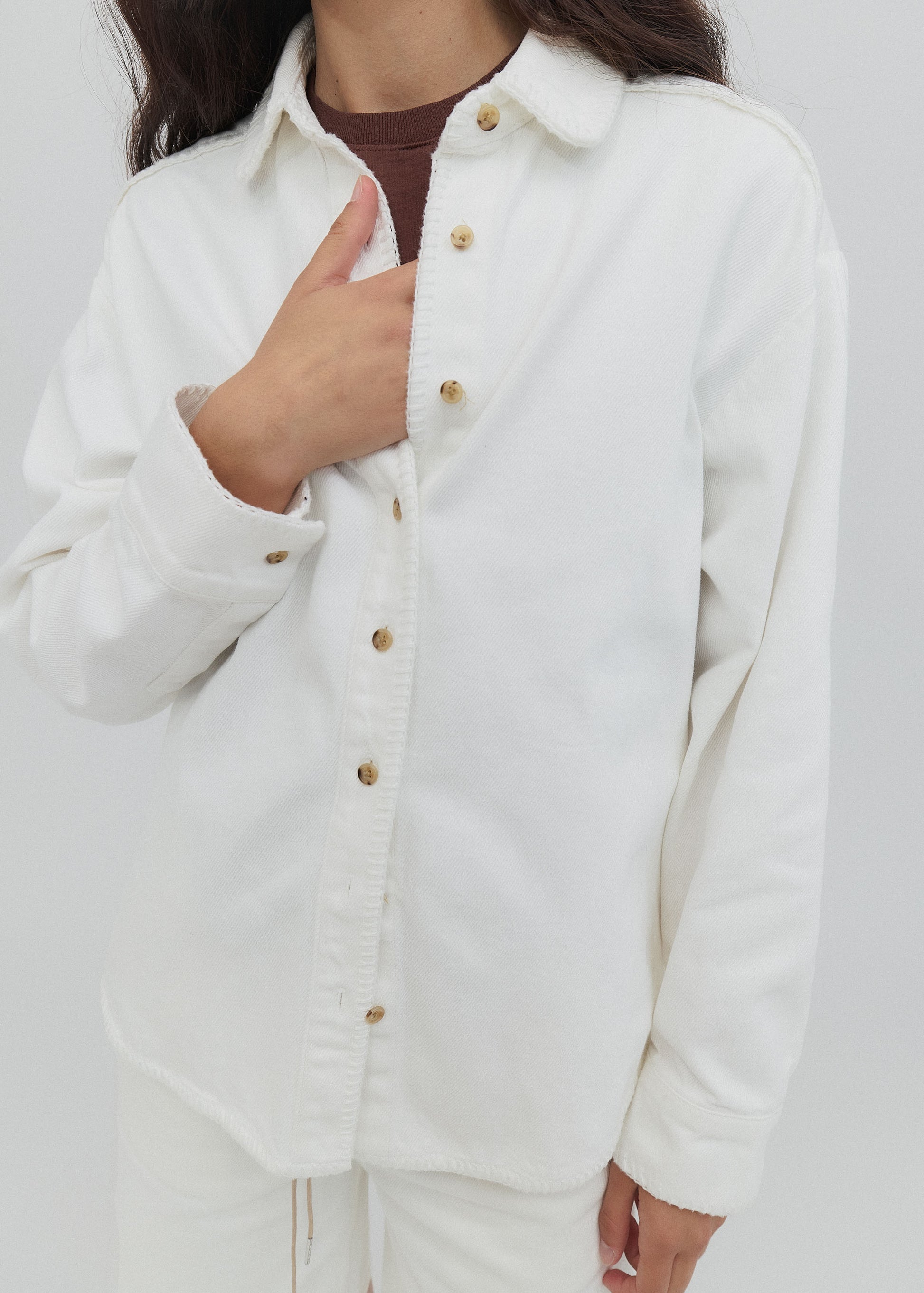 Person wearing a white jacket with gold buttons on a plain background