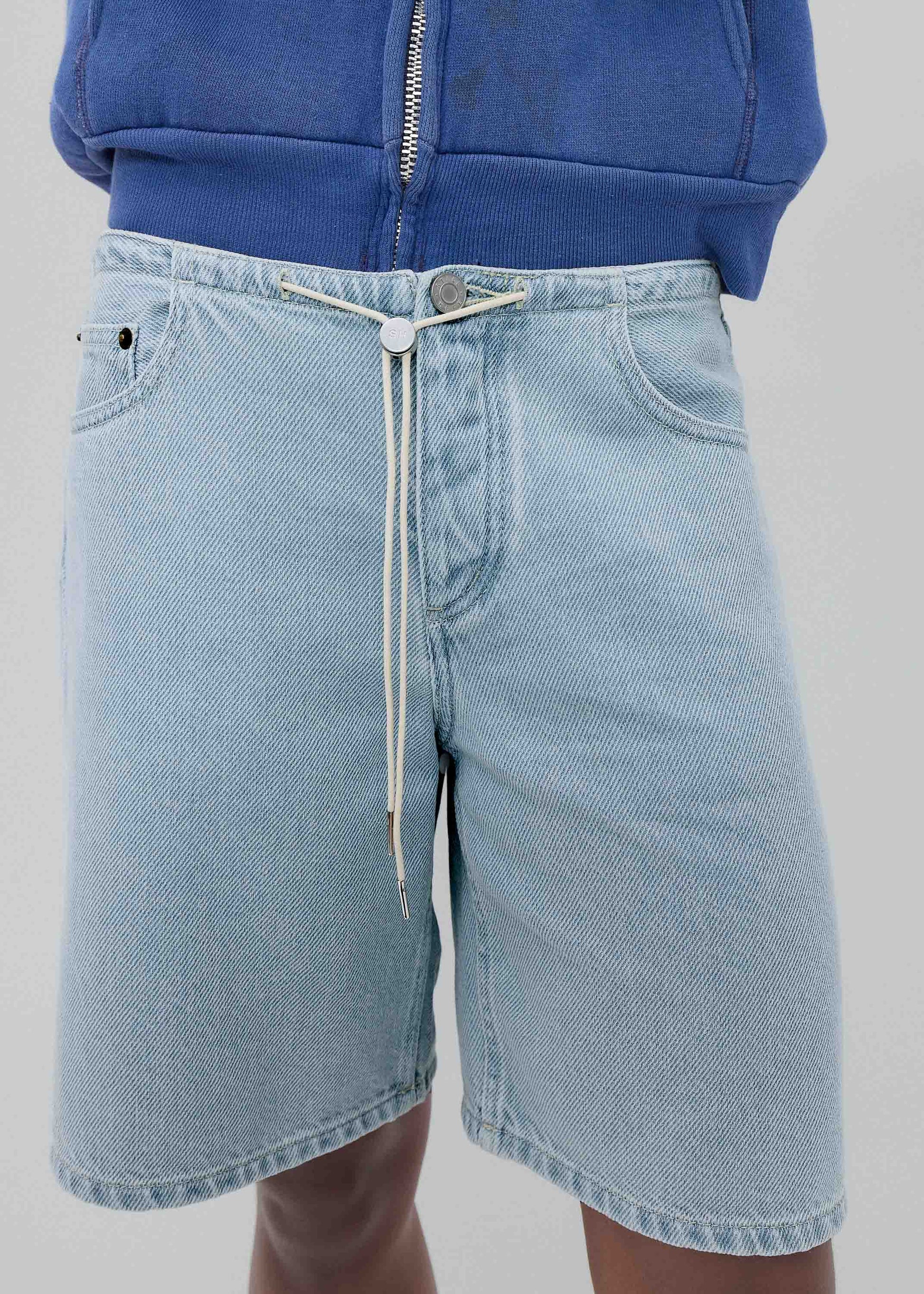Light blue denim shorts worn by a person on a plain background