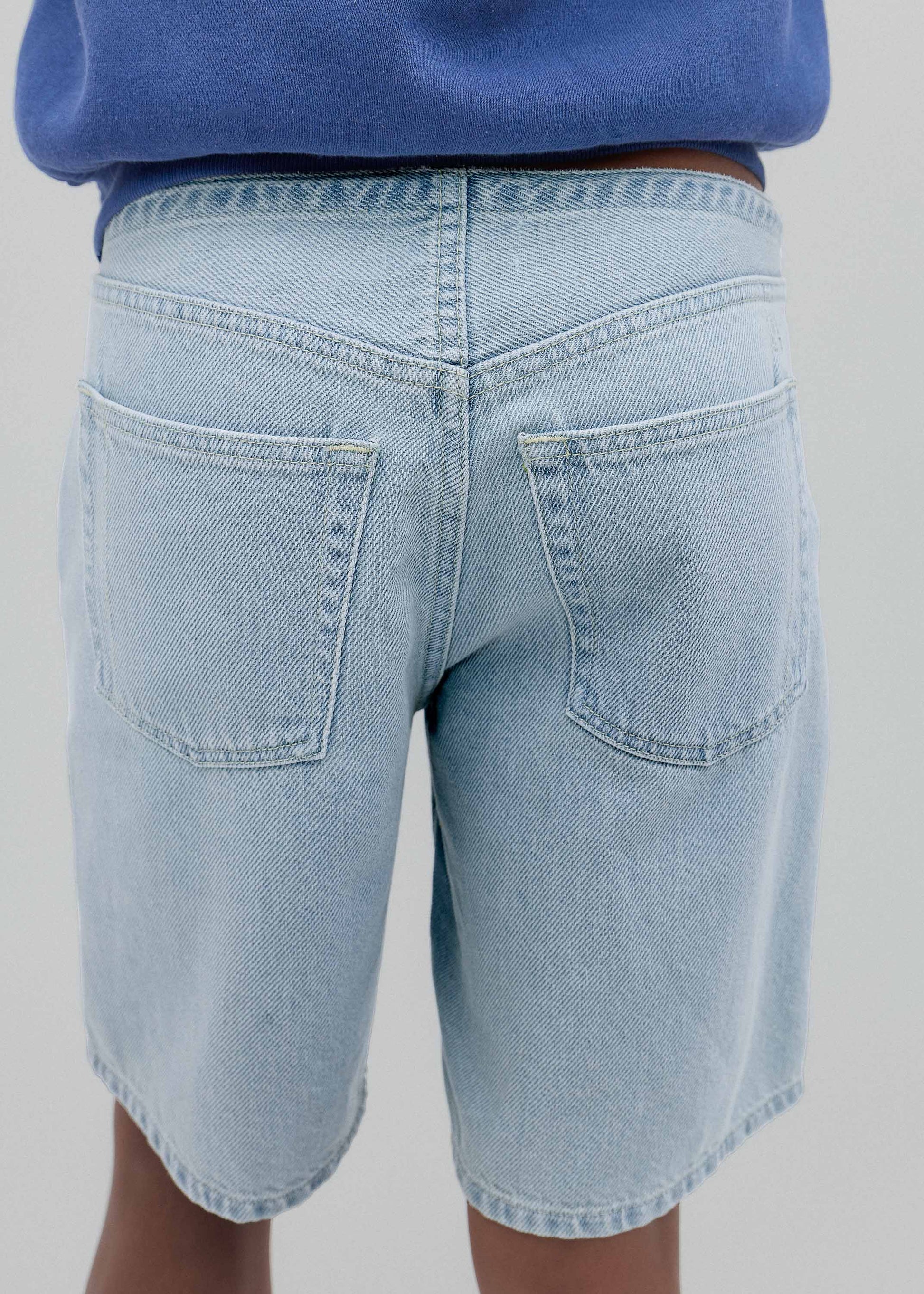 Light blue denim shorts worn by a person on a plain background