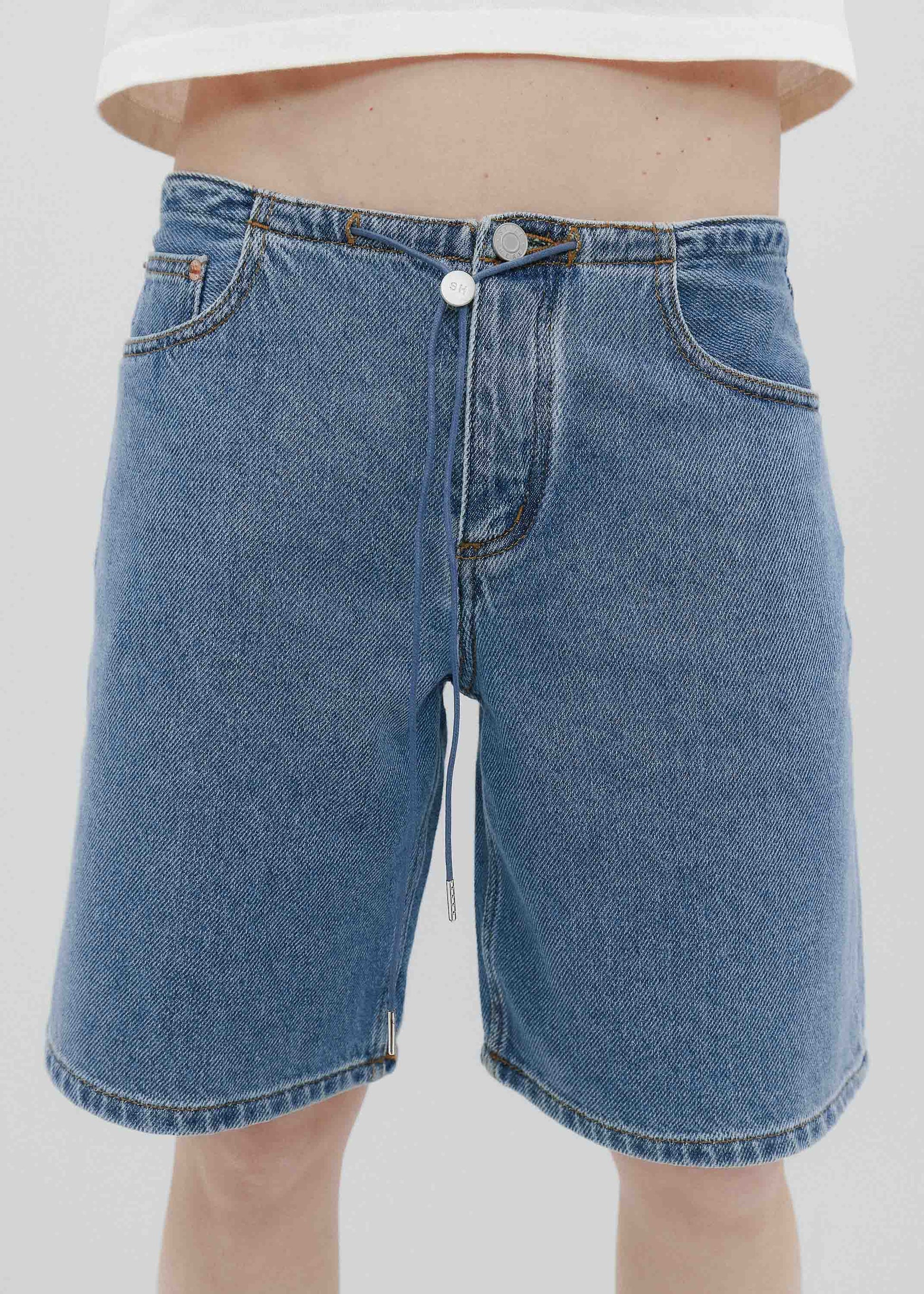 Blue denim shorts worn by a person on a white background