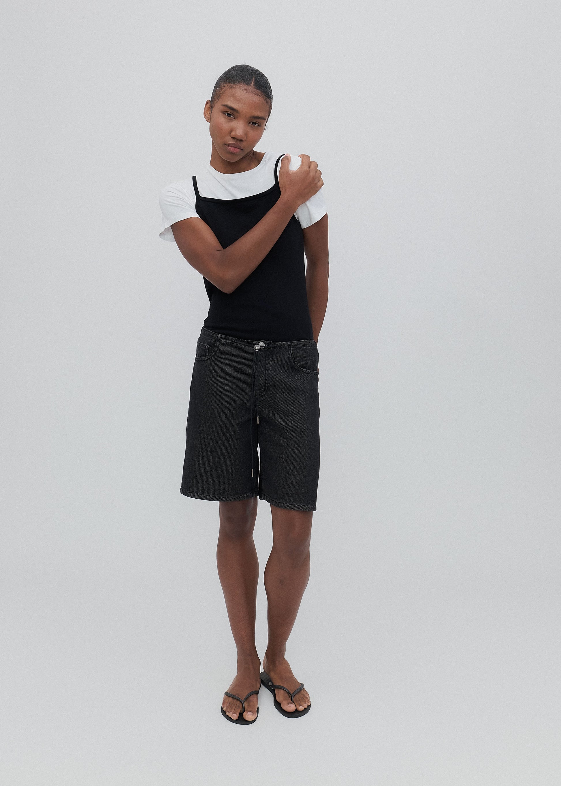 Person wearing a black tank top and shorts on a white background