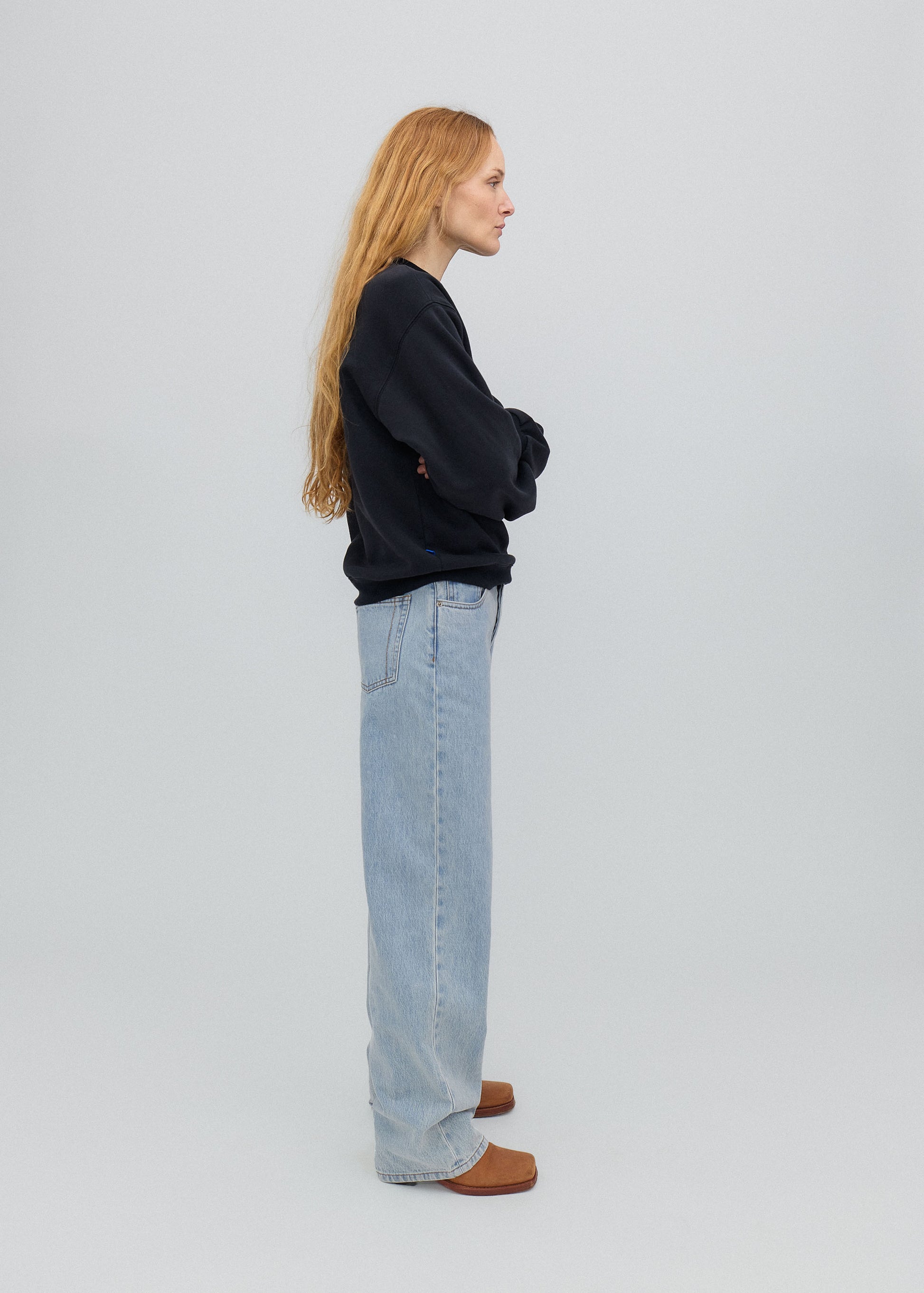 Person wearing a black sweater and light blue jeans on a white background