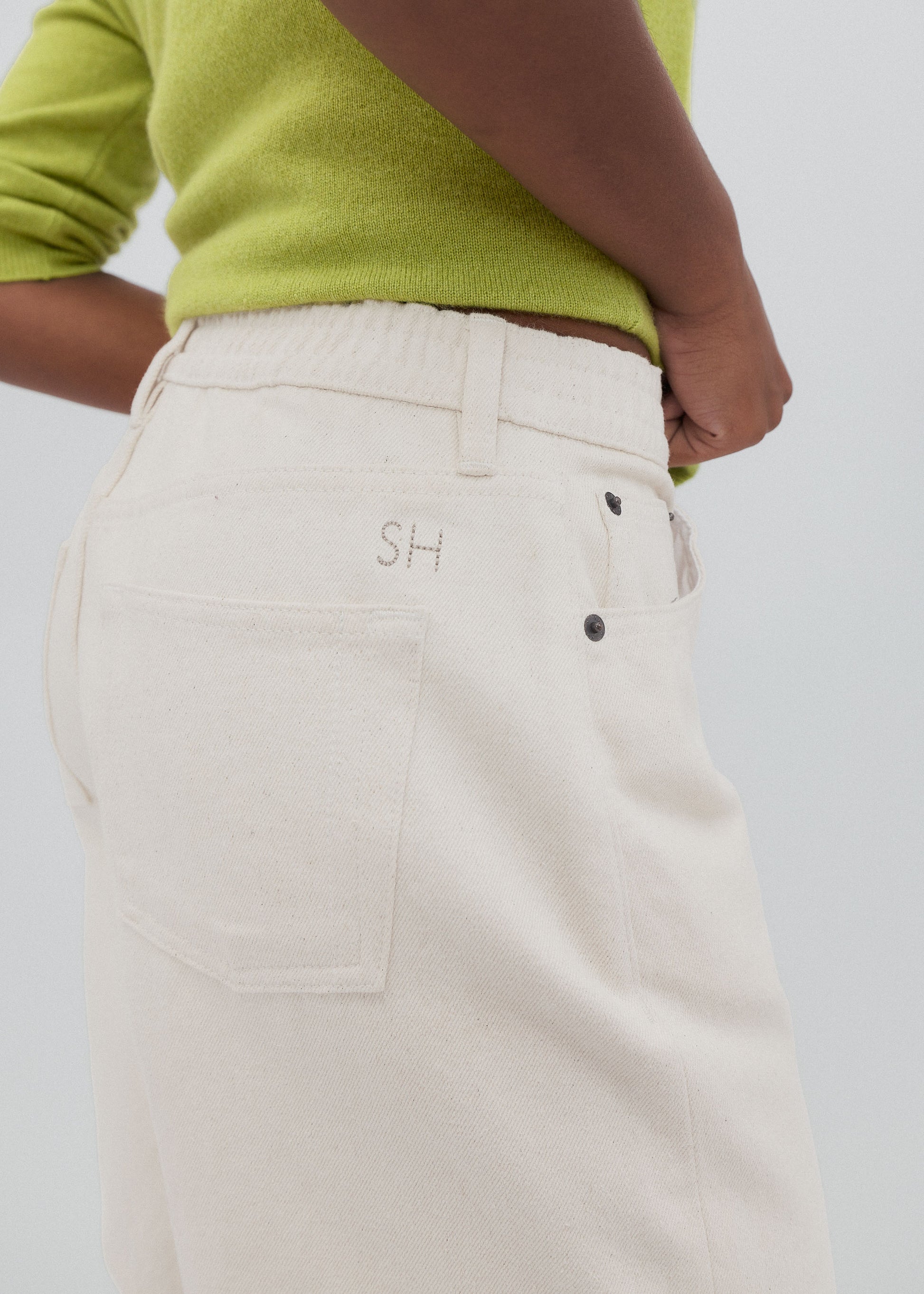 Beige pants with initials embroidered on a plain background