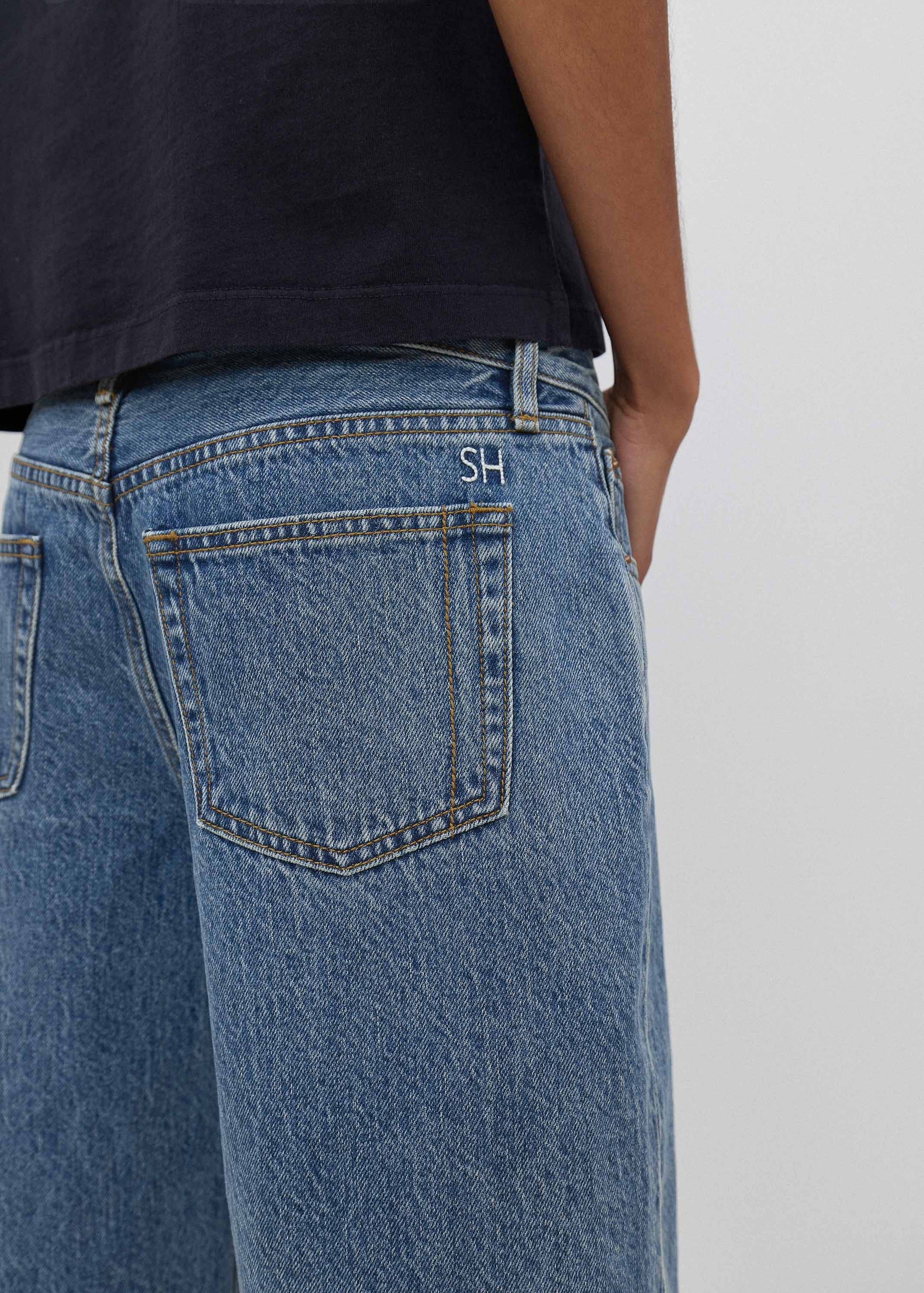 Blue jeans with a brand logo on the pocket against a neutral background