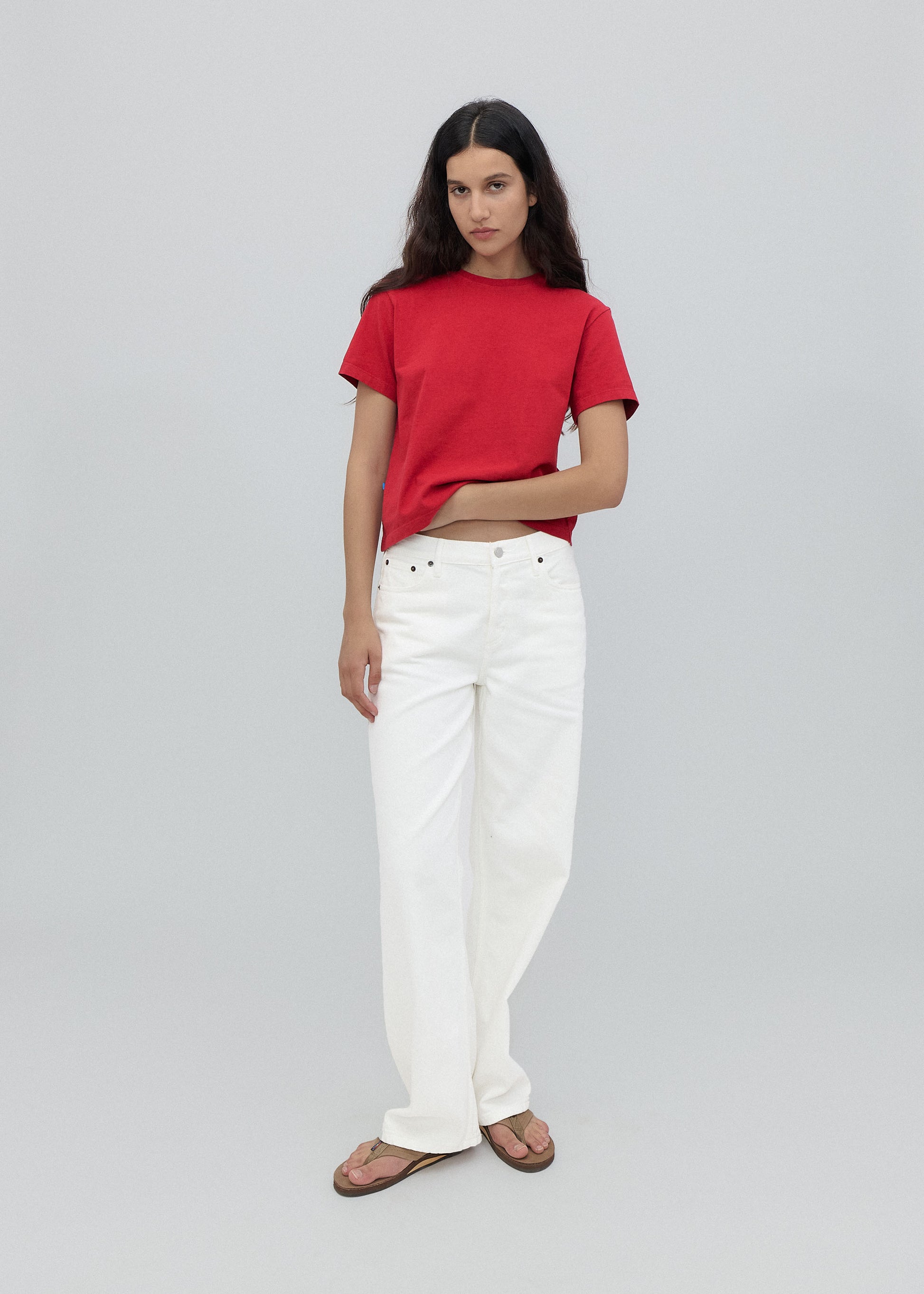 Person wearing a red shirt and white pants on a light gray background