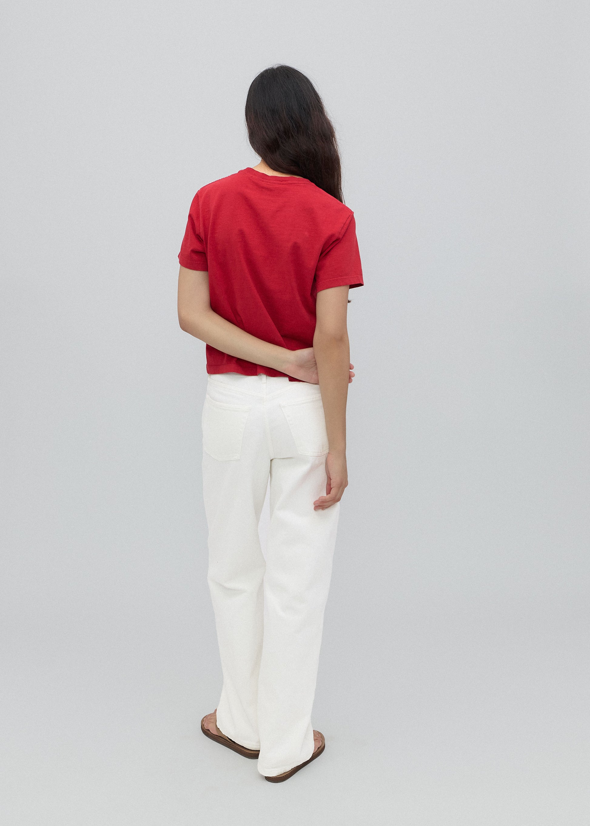 Person wearing a red shirt and white pants on a gray background