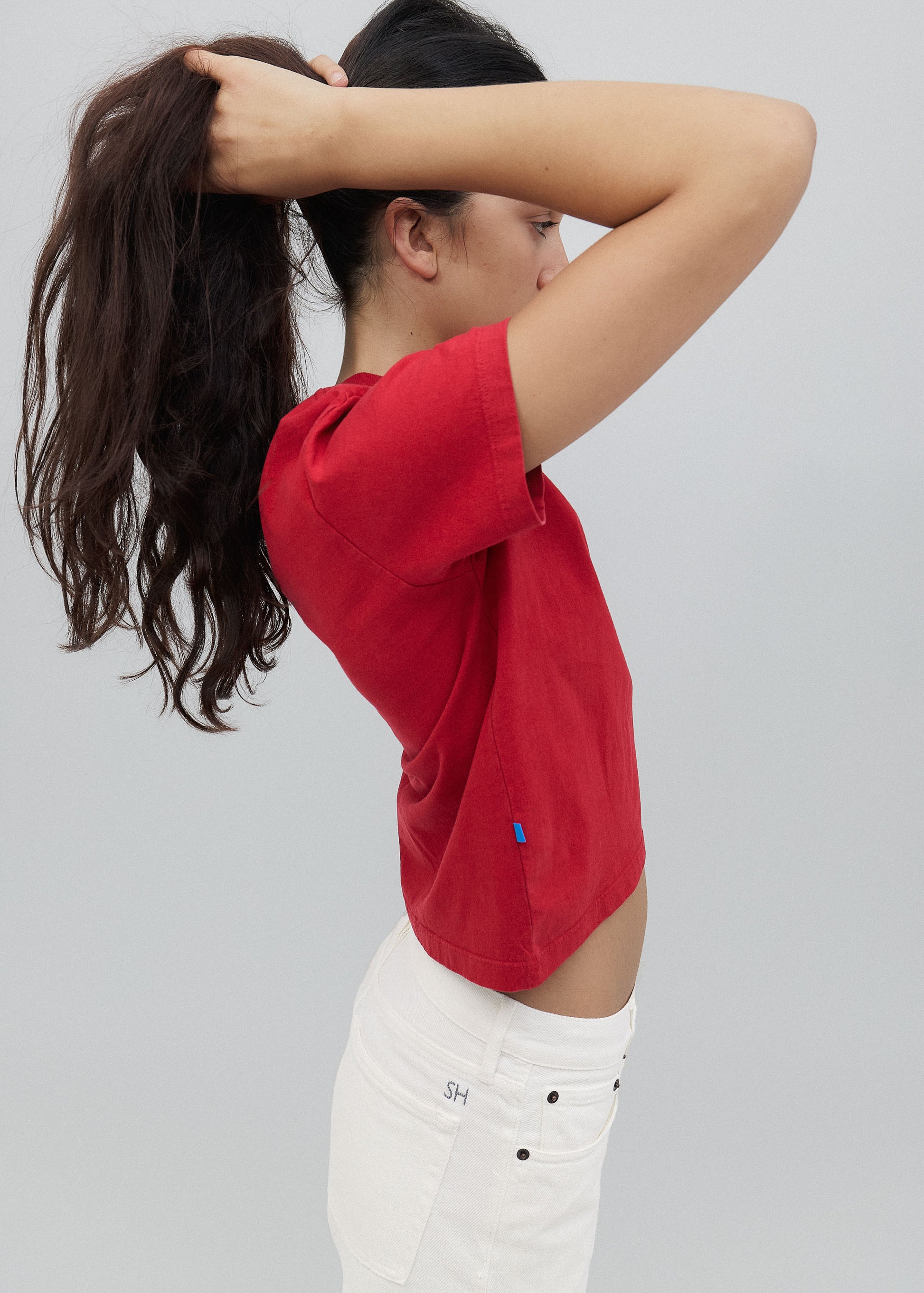 Person wearing a red shirt and white pants with a gray background