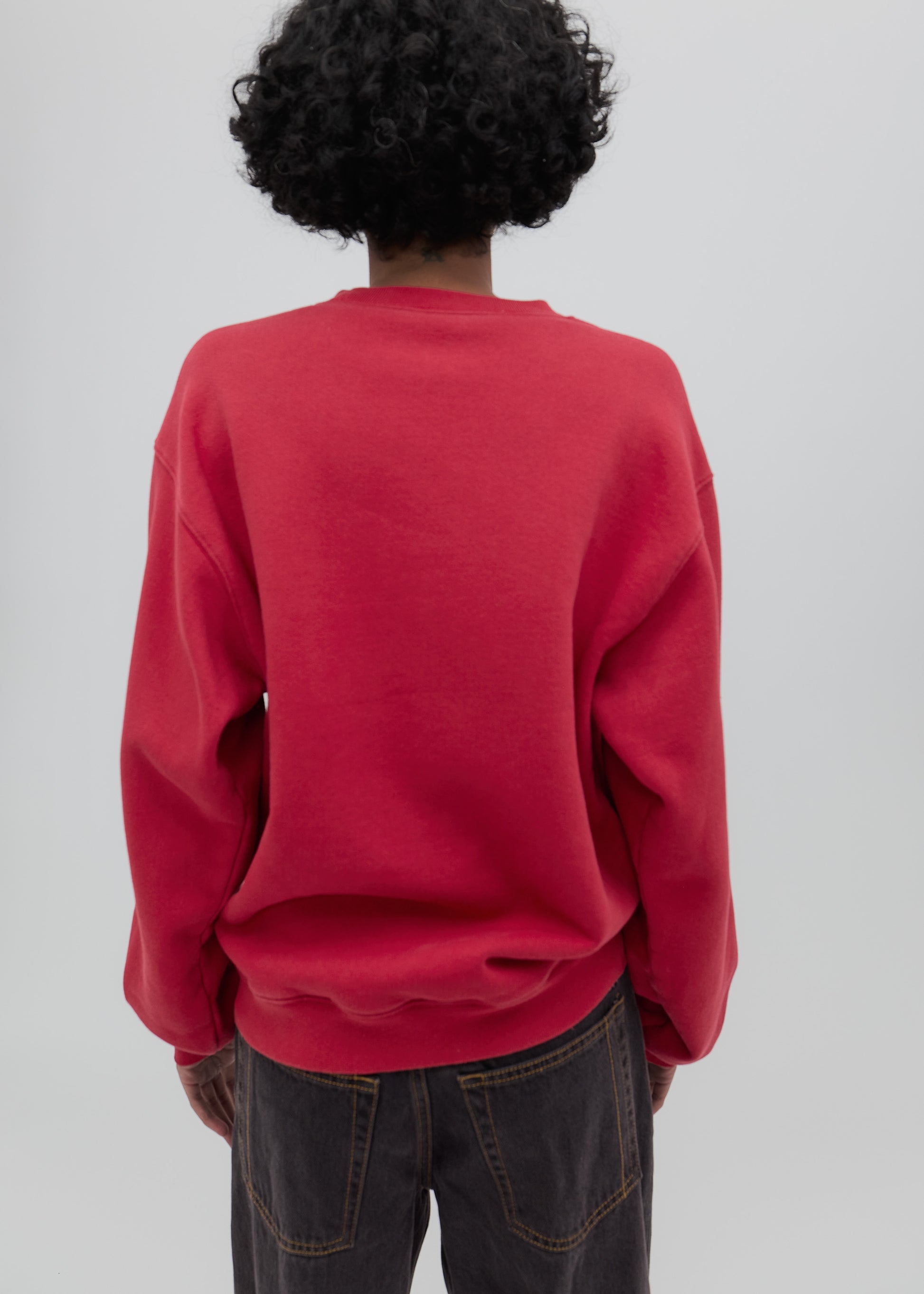 Person wearing a red sweatshirt from behind on a plain background