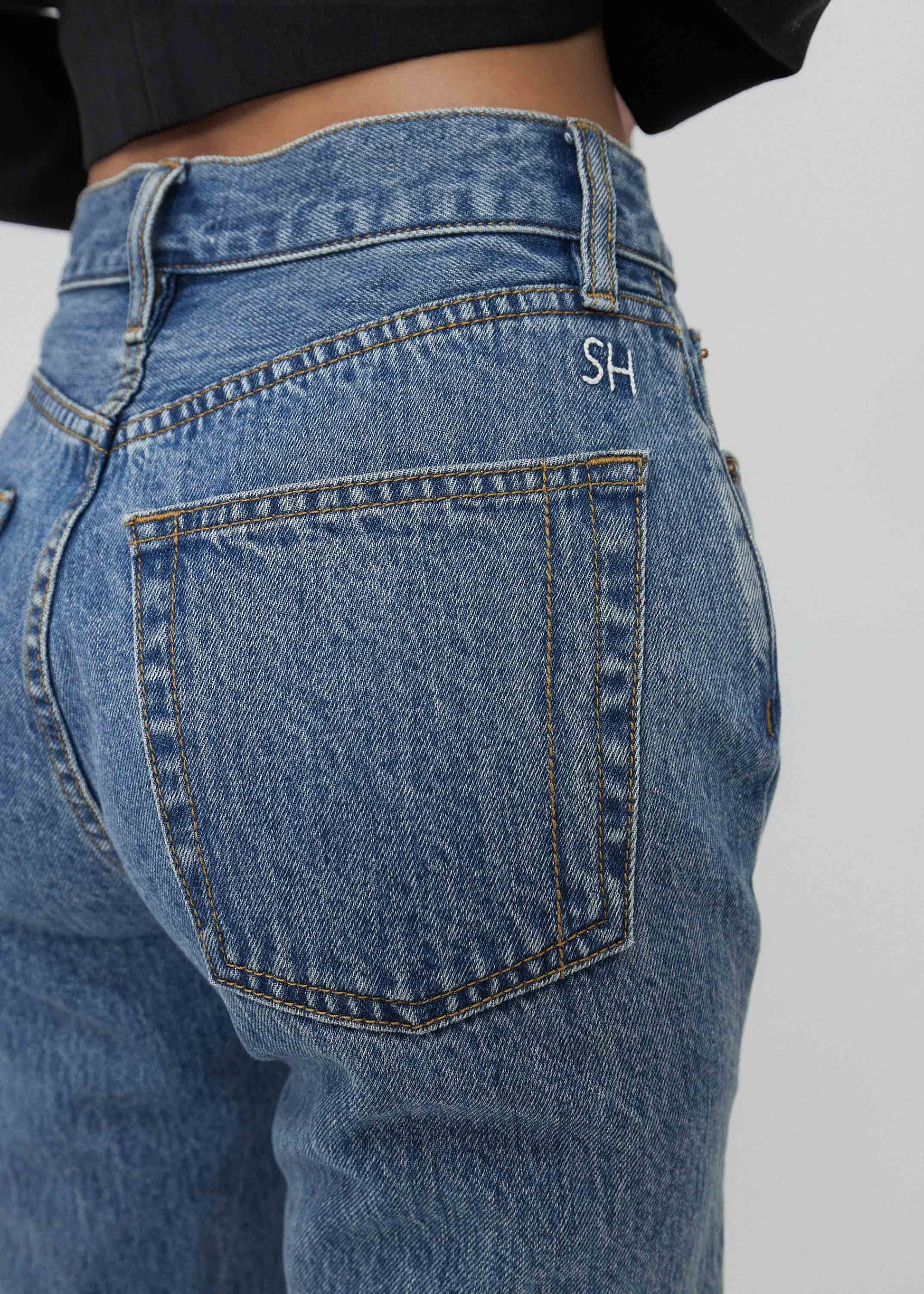 Close-up of blue jeans with a brand logo on a plain background