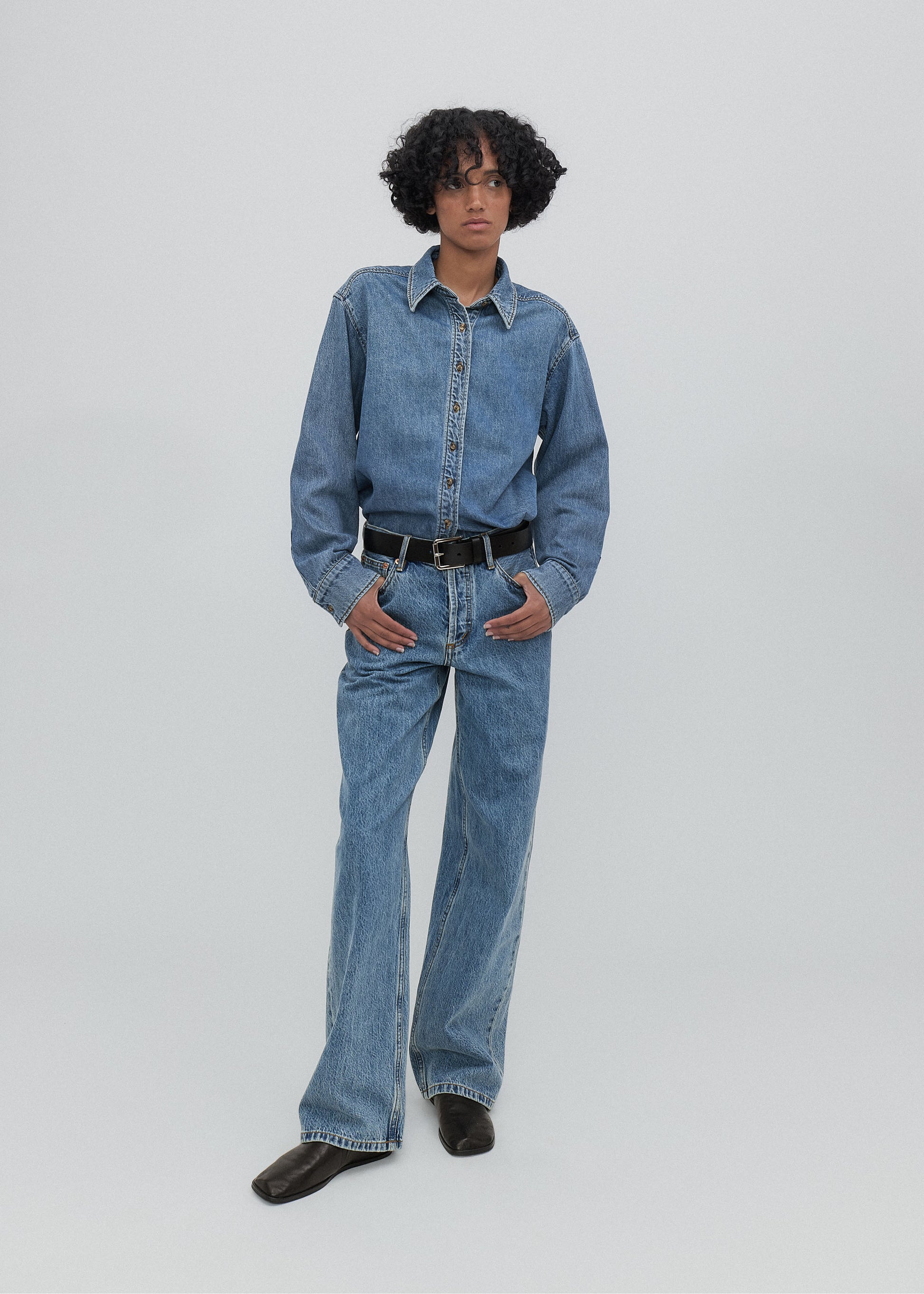 Person wearing a blue denim outfit on a plain background