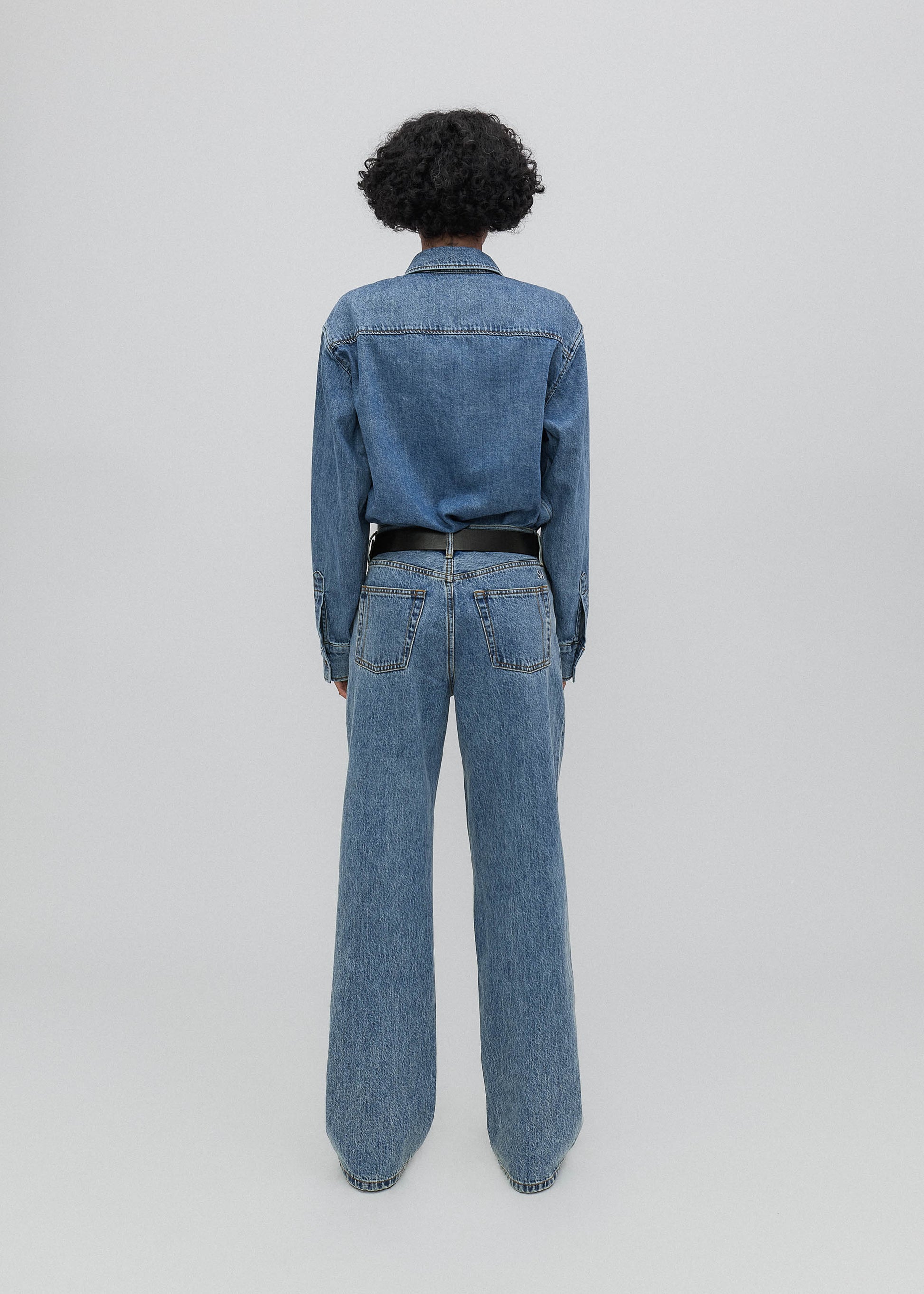 Person wearing a blue denim outfit on a light gray background