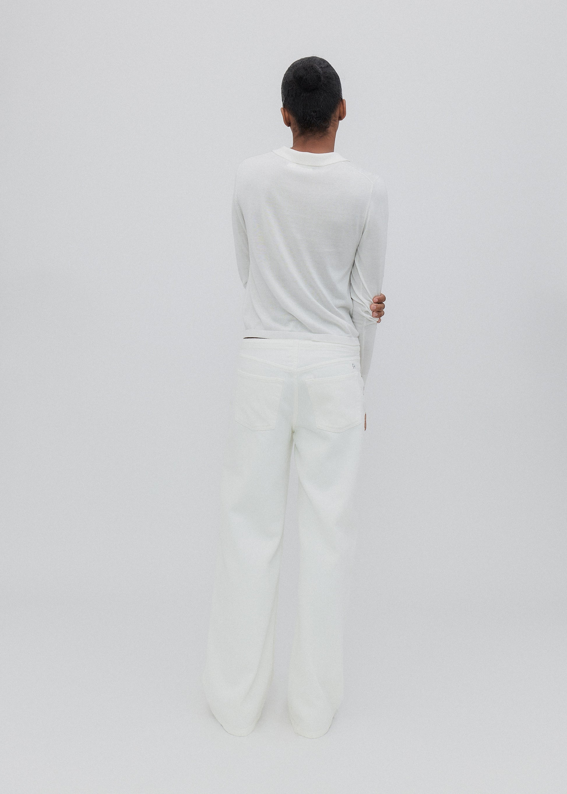 Person wearing a white outfit standing against a plain background