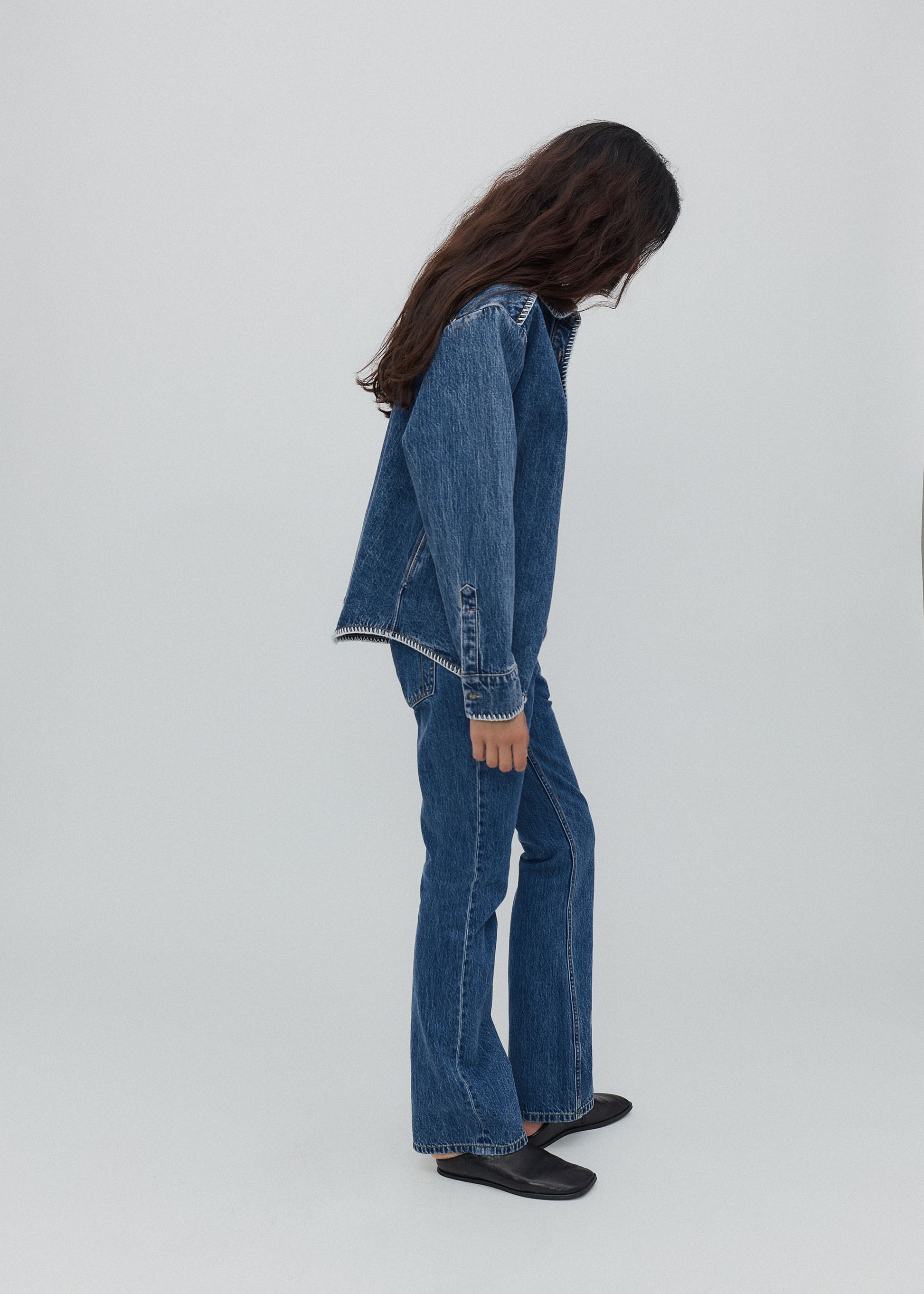 Person wearing a denim jacket and jeans on a white background