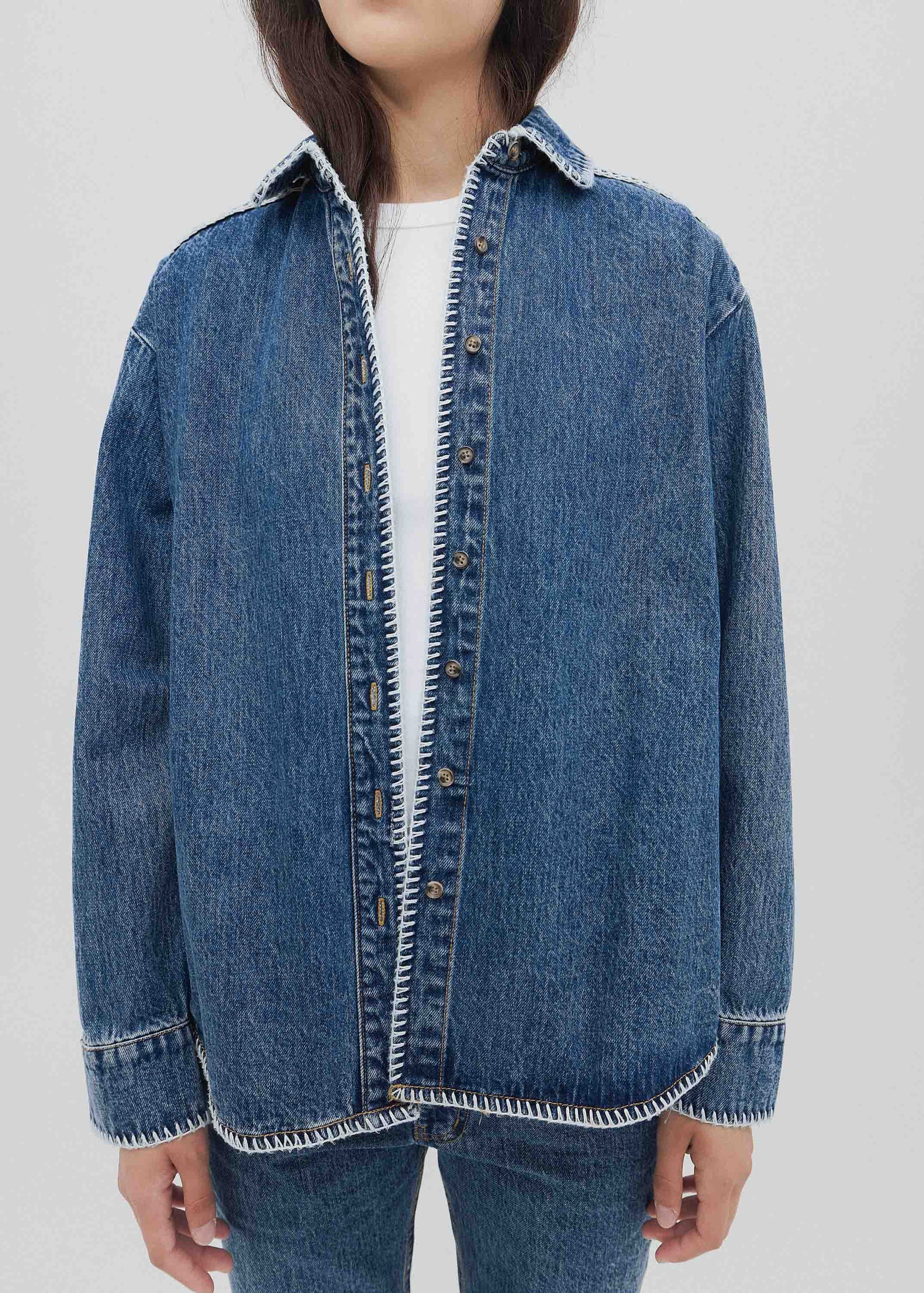 Person wearing a blue denim jacket on a white background