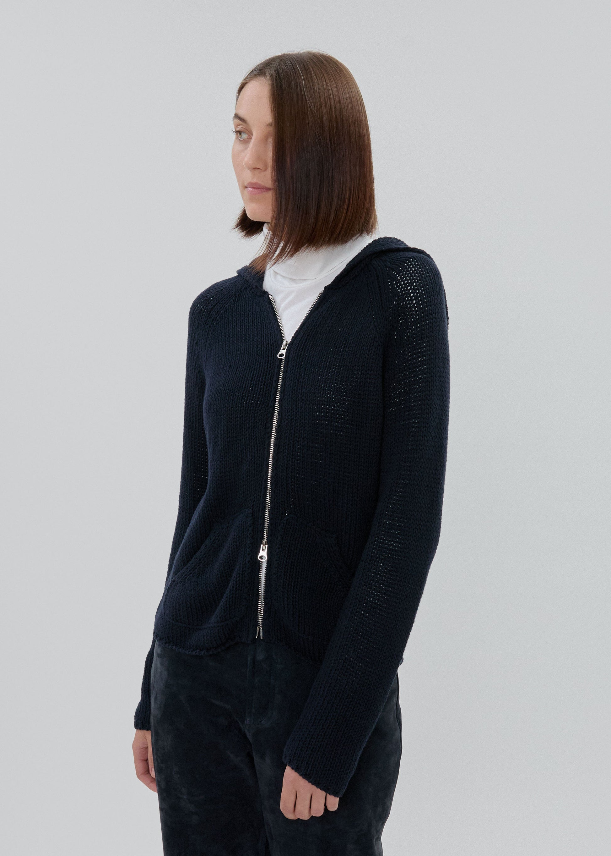 Person wearing a dark blue zip-up hoodie on a light gray background