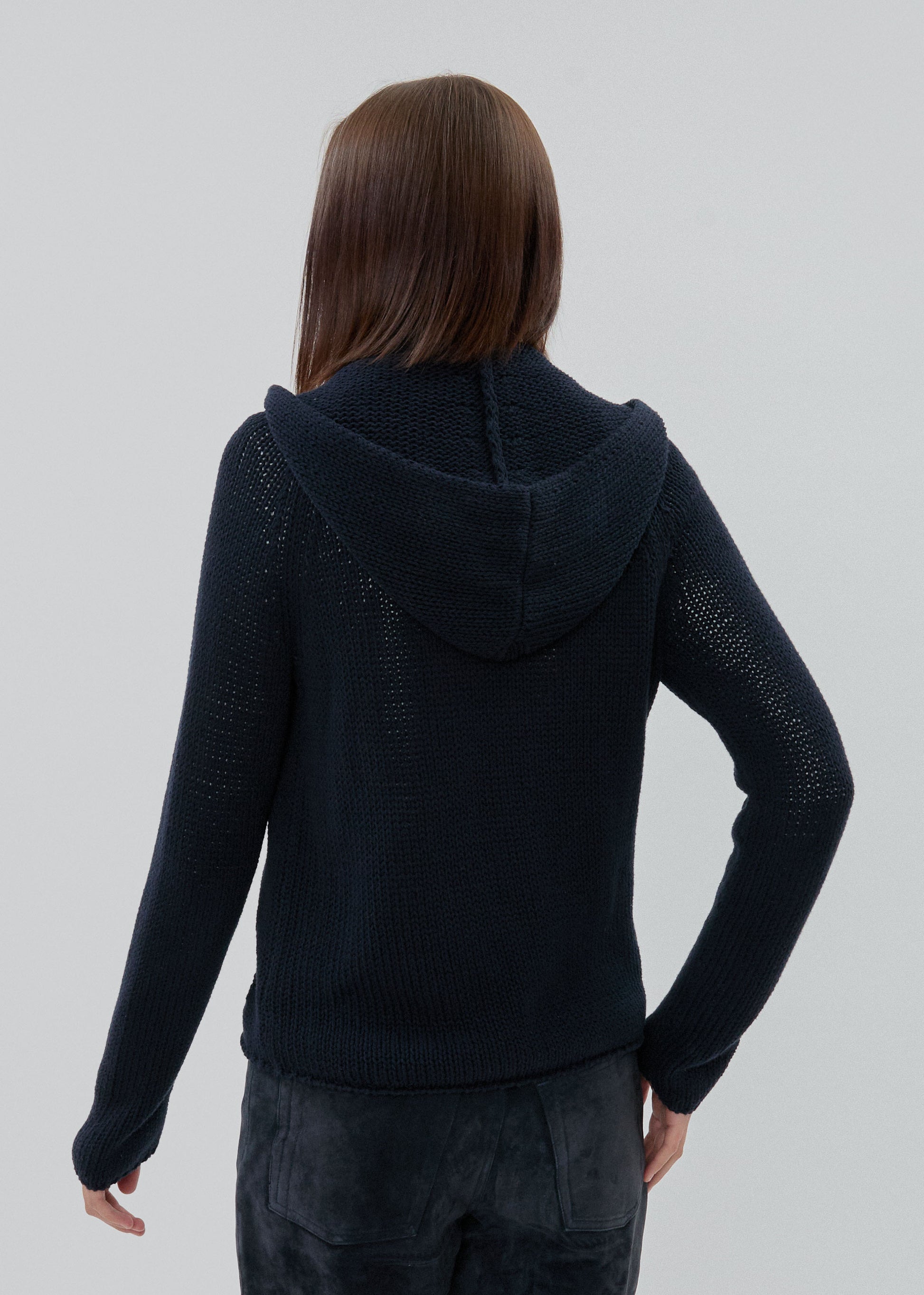 Person wearing a black textured hoodie on a plain background