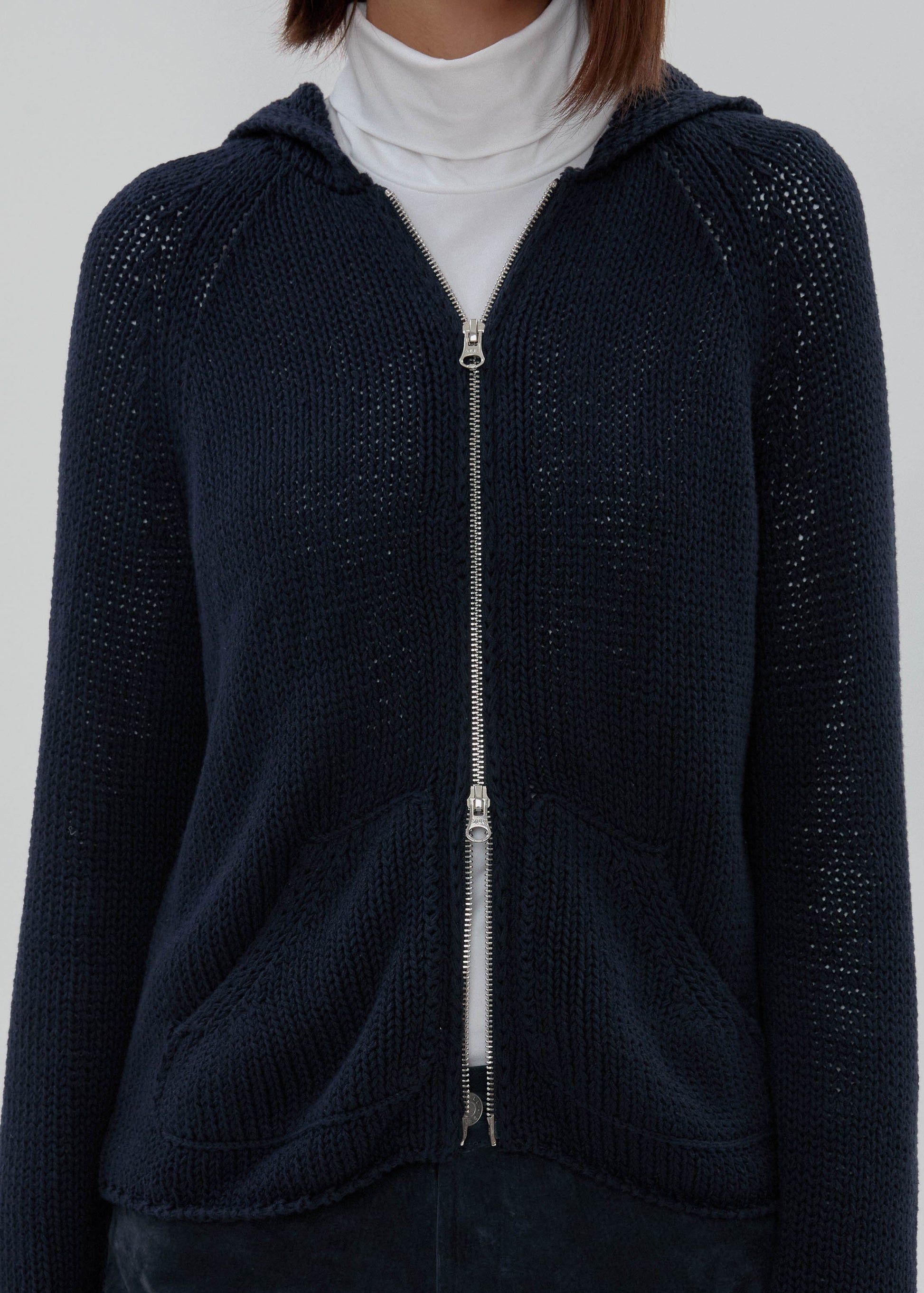 Navy blue zip-up hoodie worn by a person on a plain background