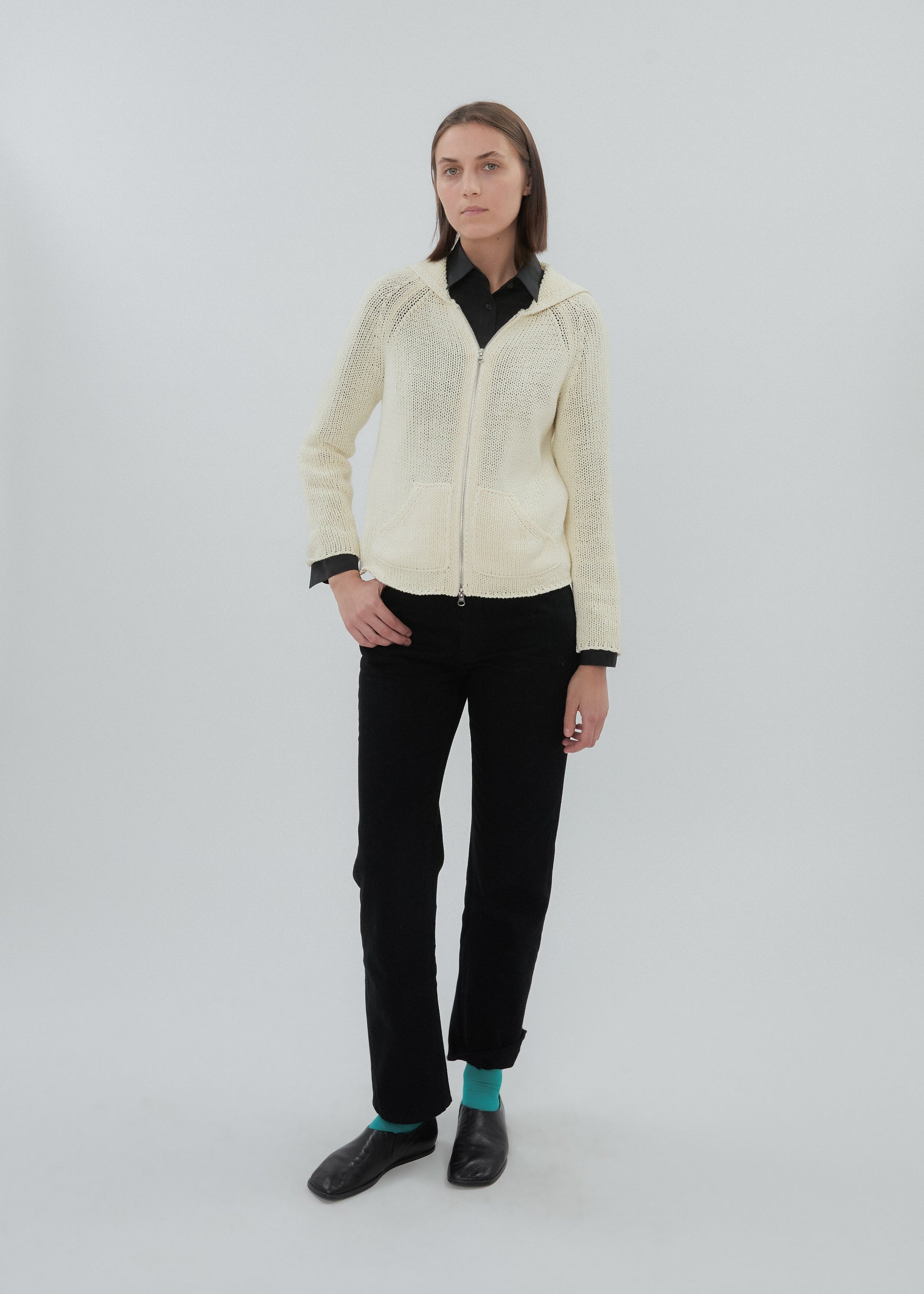 Person wearing a cream-colored zip-up hoodie and black pants on a white background