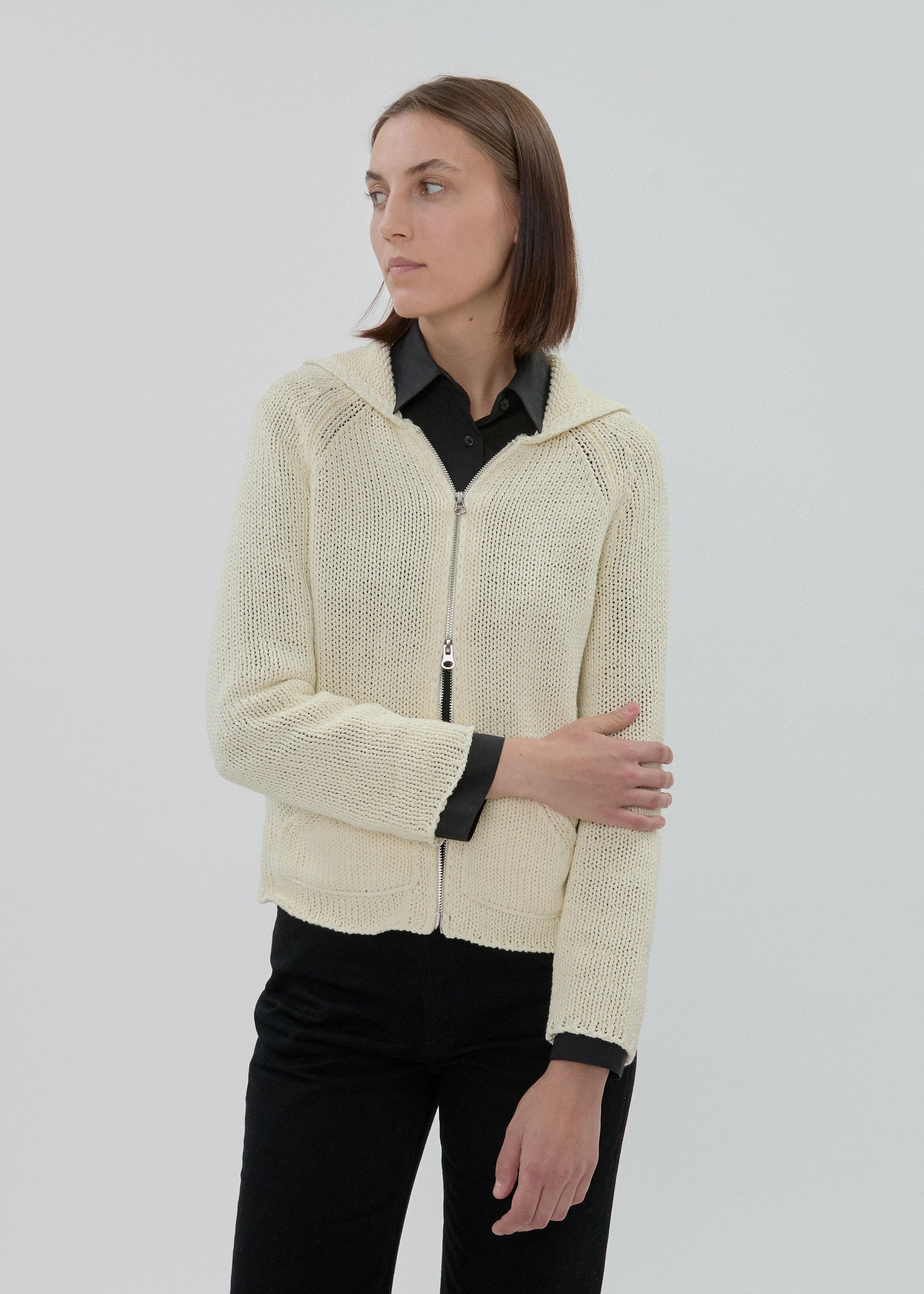 Woman wearing a cream knitted jacket on a plain background