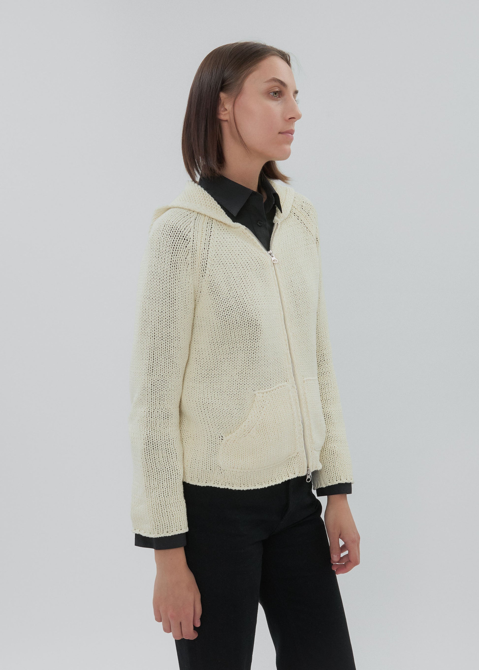 Woman wearing a cream knitted jacket on a white background