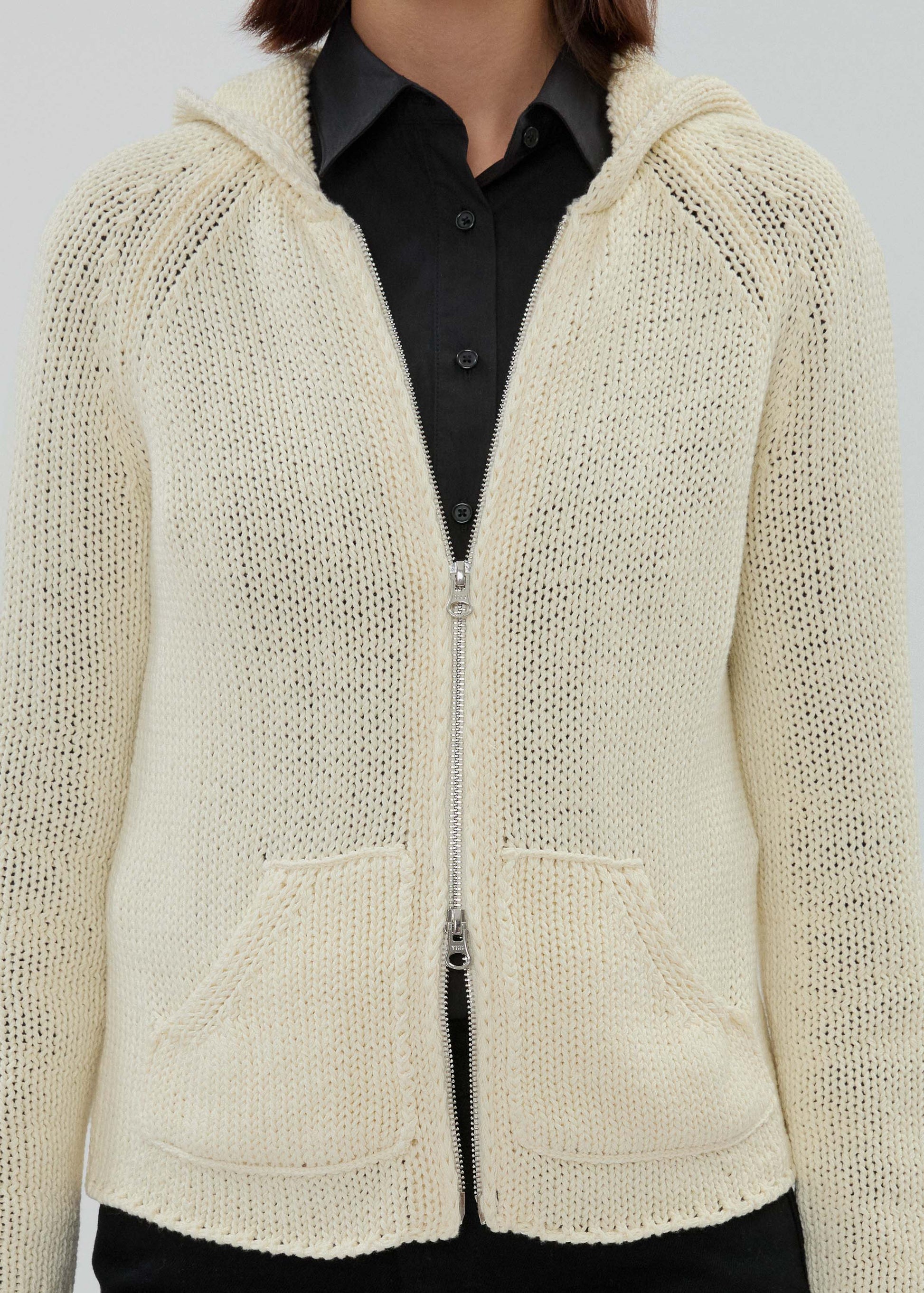 Beige knitted cardigan with a zipper worn by a person on a plain background