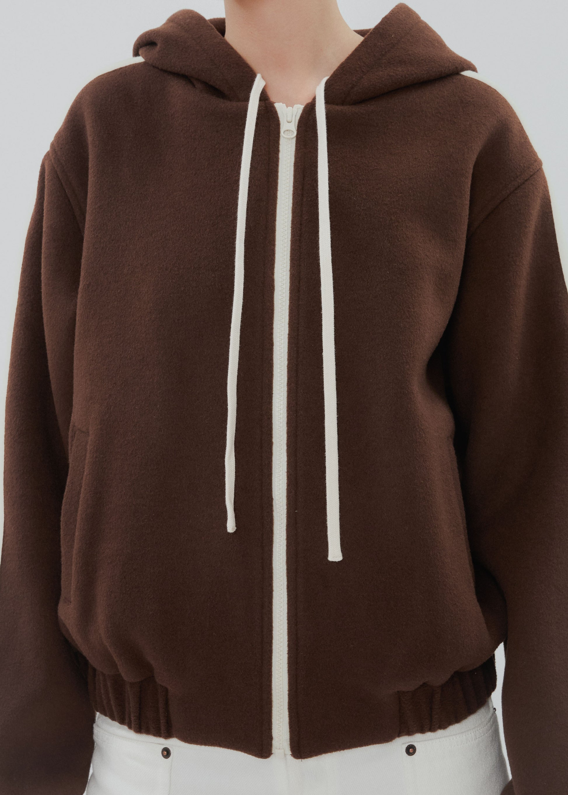 Brown hoodie with white drawstrings on a plain background