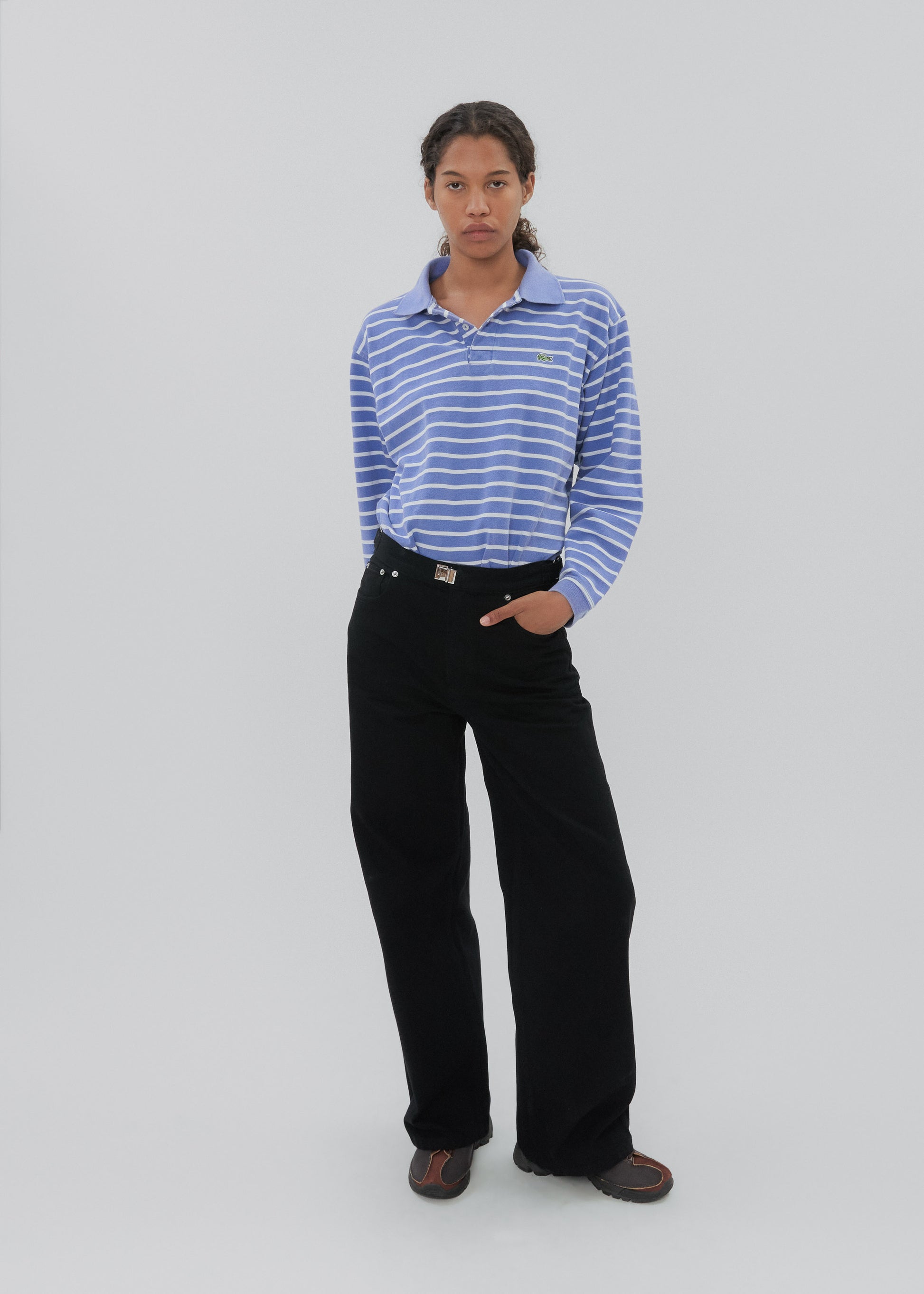Person wearing a blue striped shirt and black pants on a white background