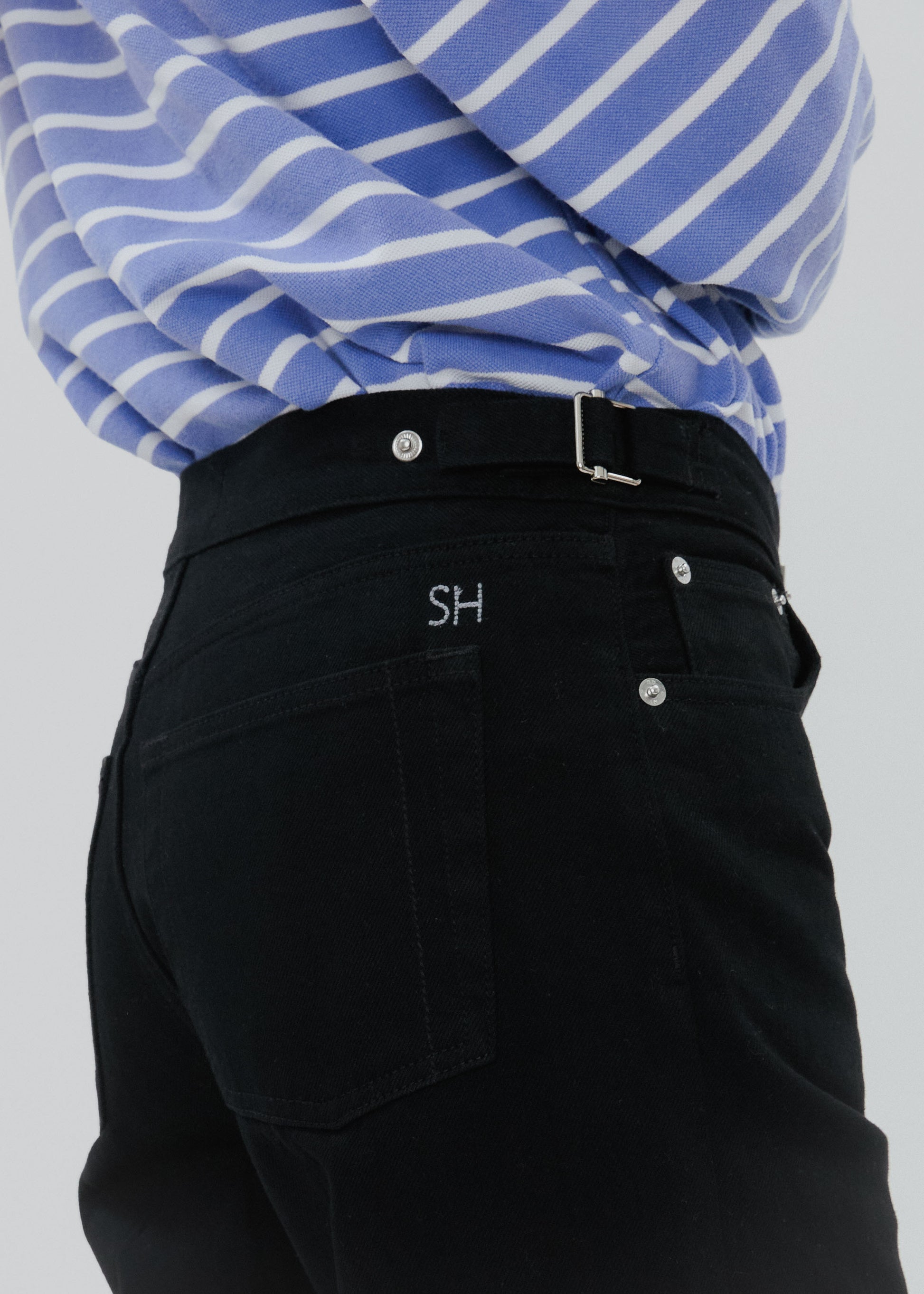 Person wearing a blue and white striped shirt with black pants featuring a logo on a light gray background