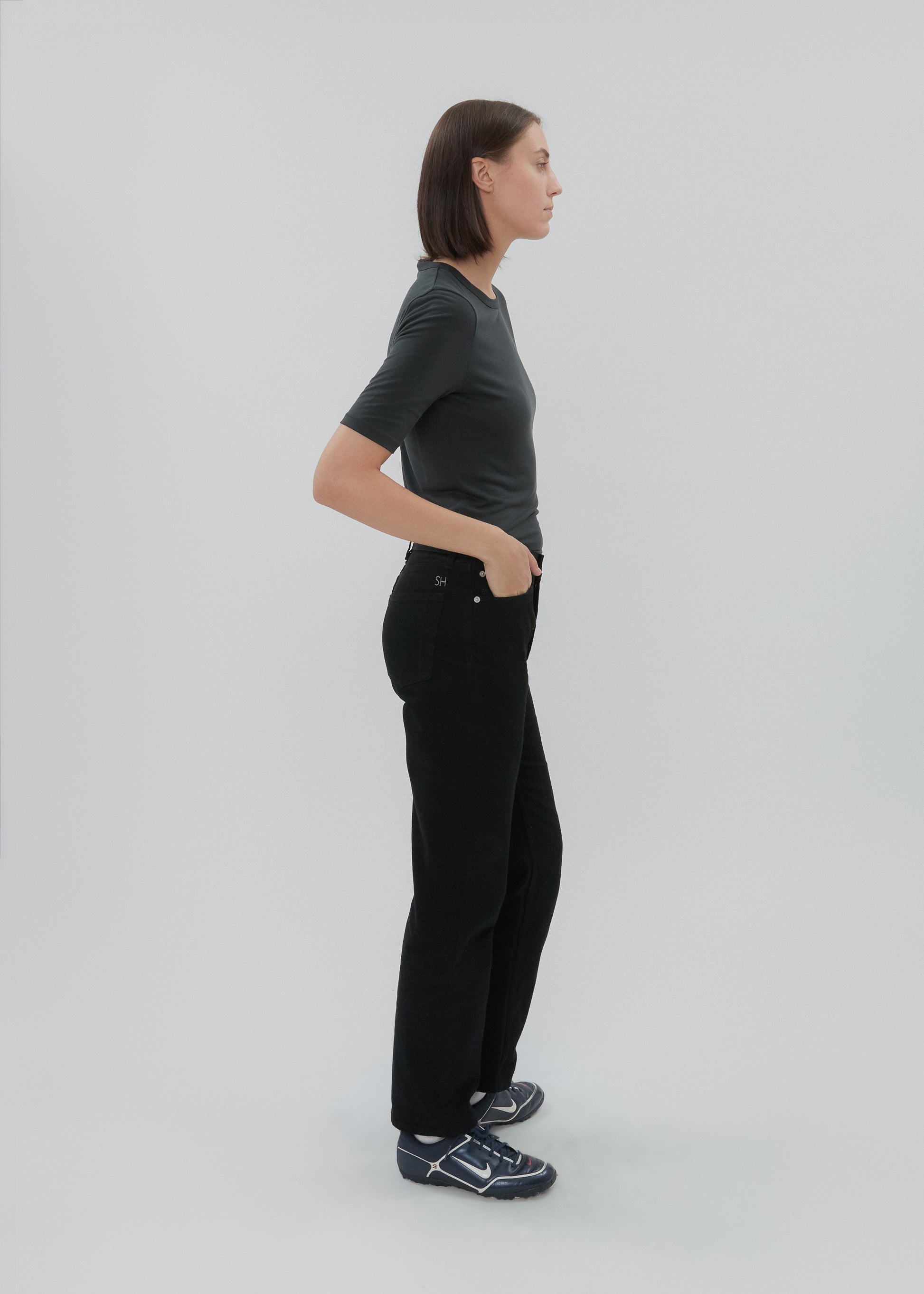 Person wearing a black t-shirt and black pants standing against a white background