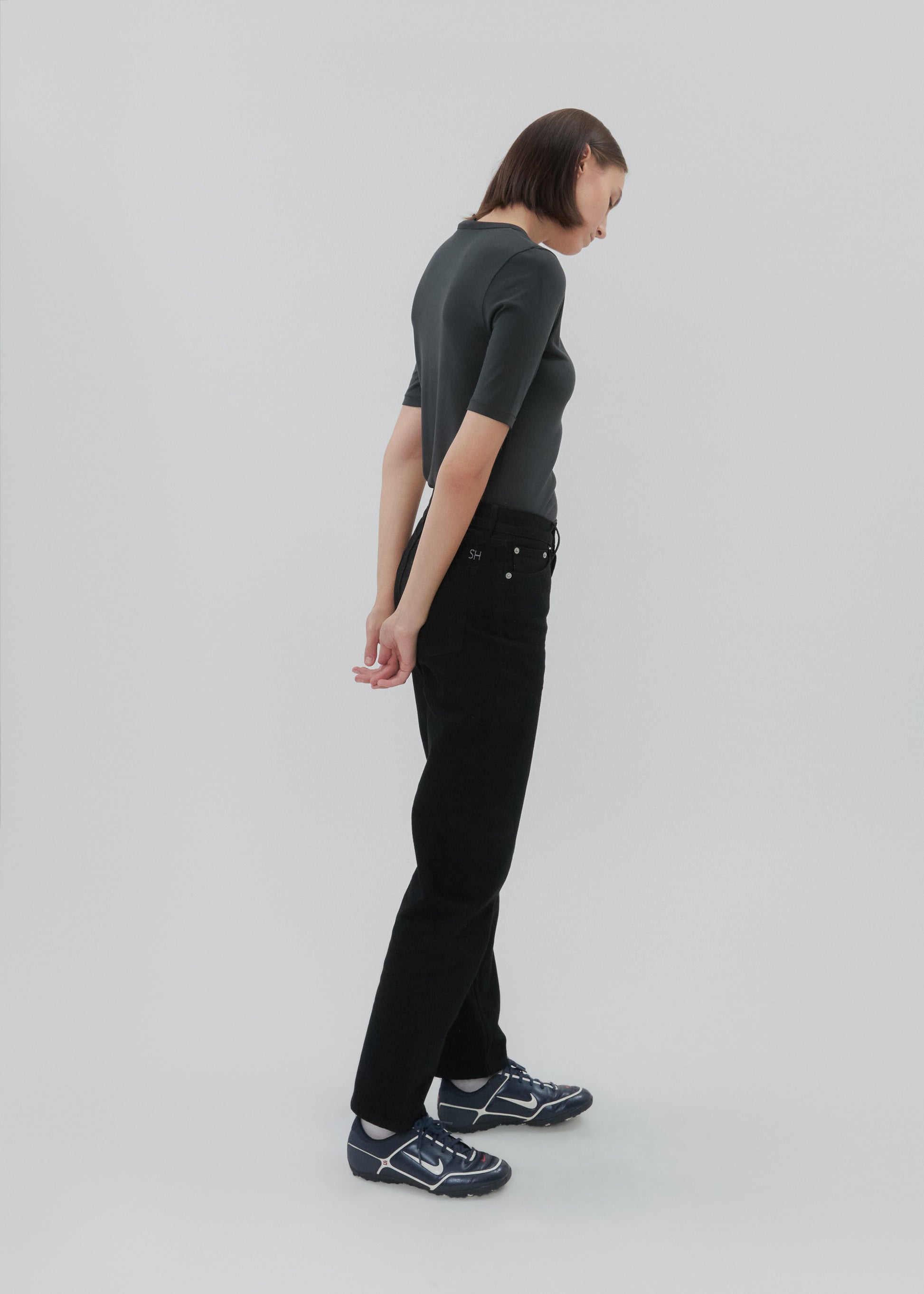 Person wearing a dark gray t-shirt and black pants on a light gray background