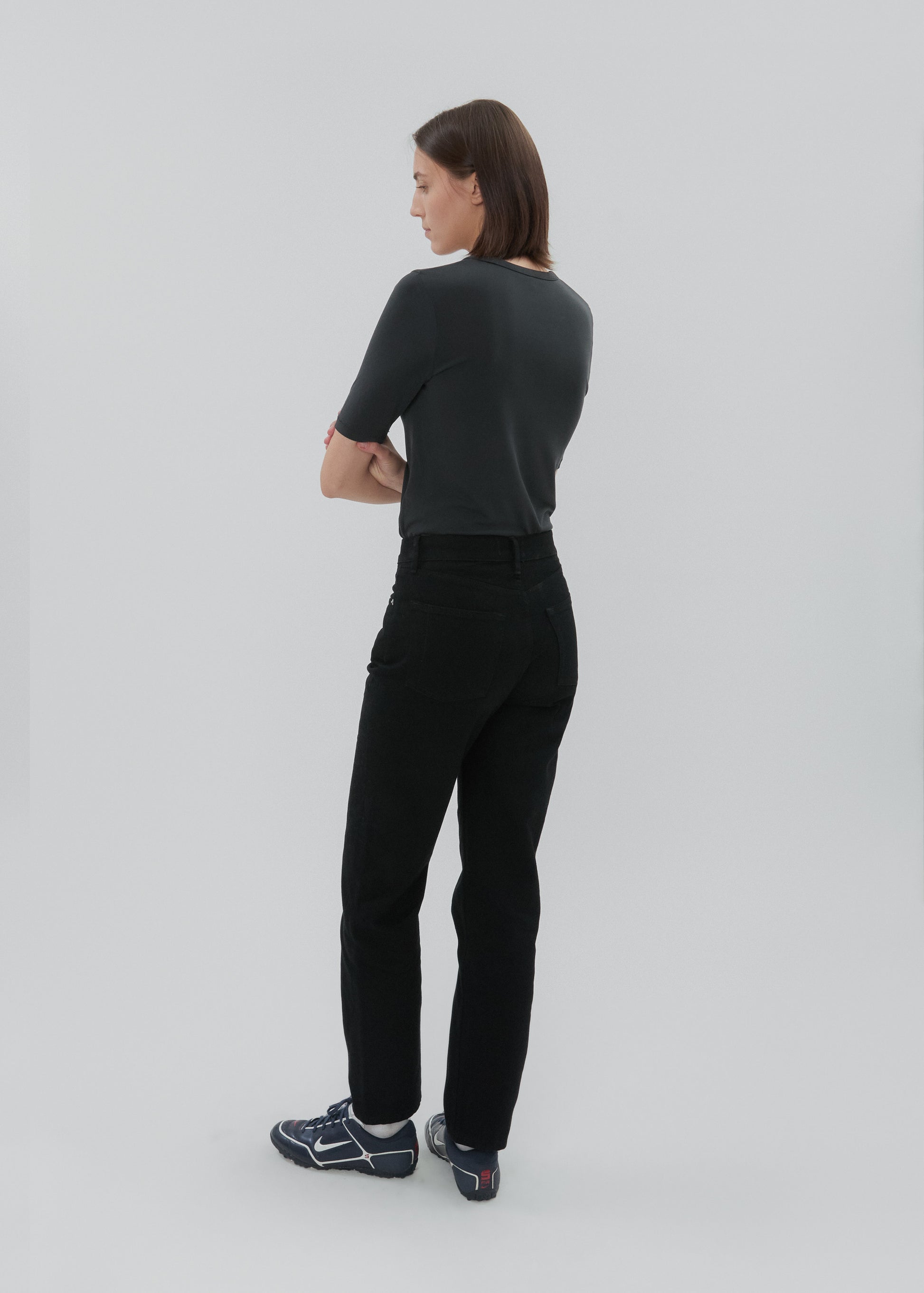 Woman wearing a black outfit standing against a plain background