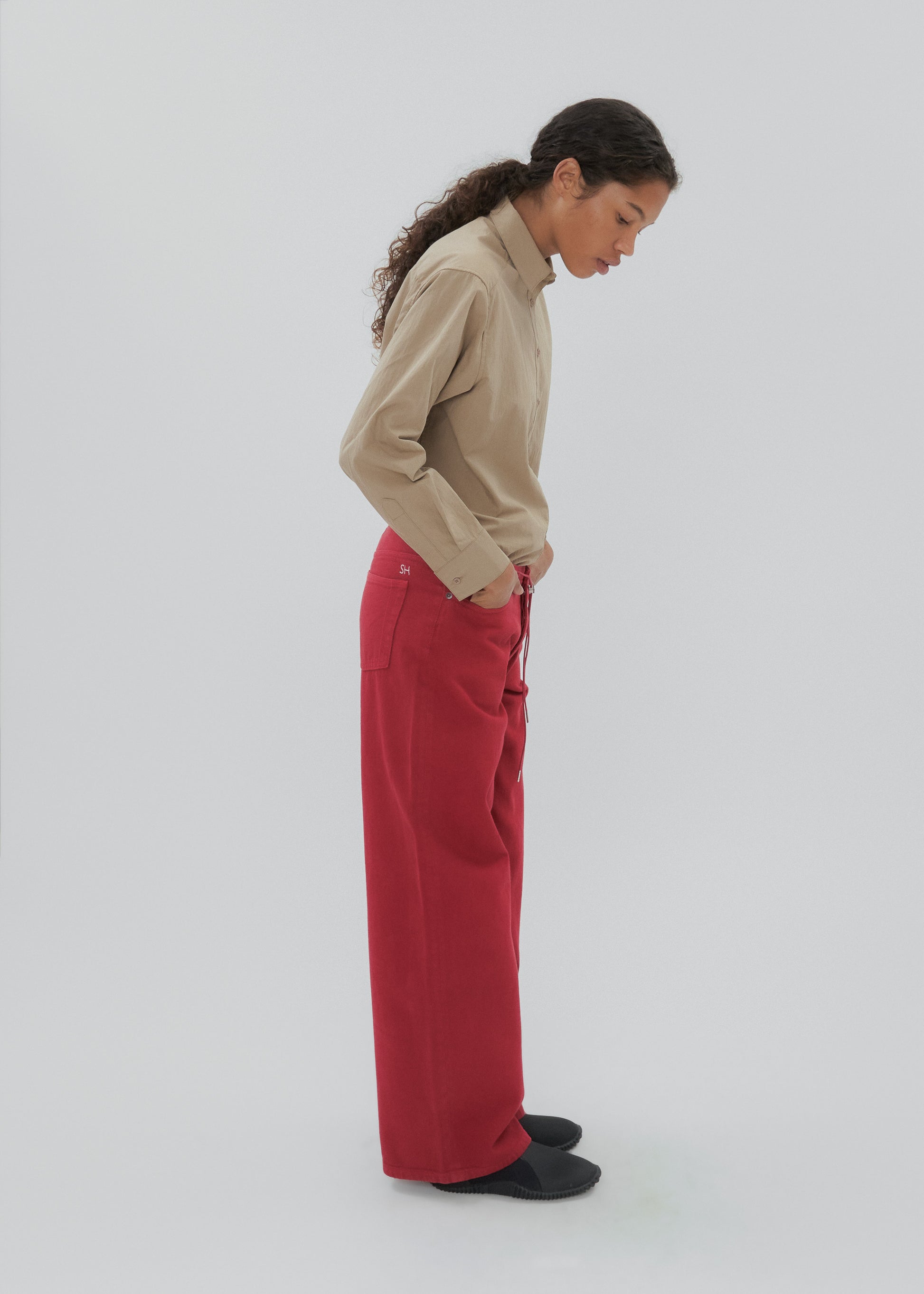 Person wearing a beige sweater and red pants on a white background
