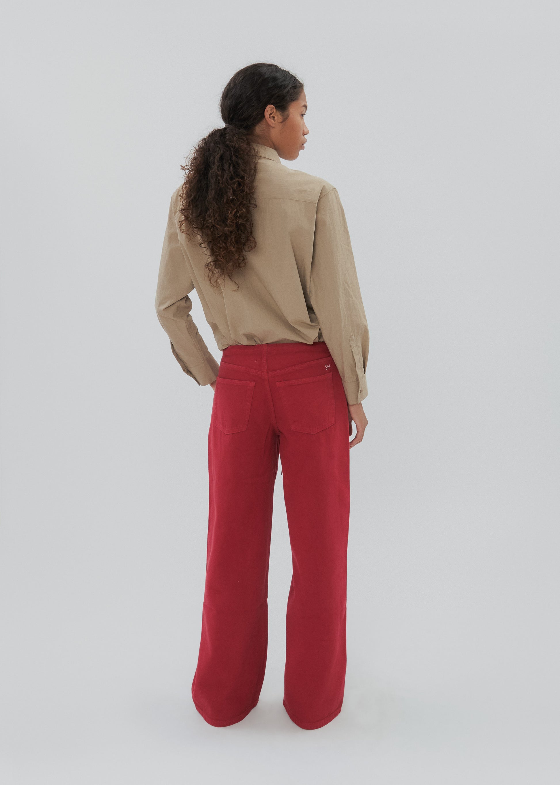 Person wearing a beige shirt and red pants on a white background