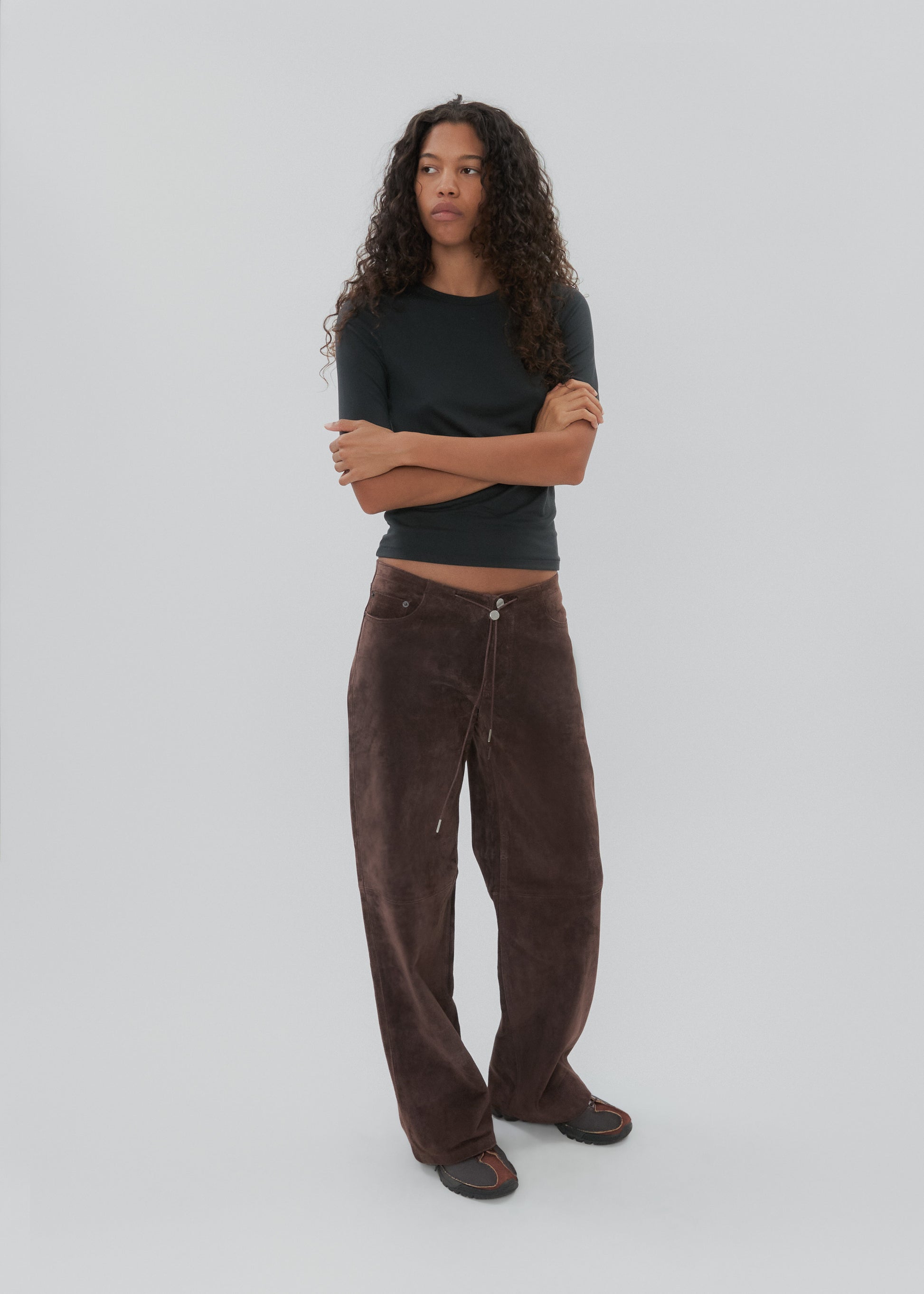 Person wearing a black shirt and brown pants on a white background