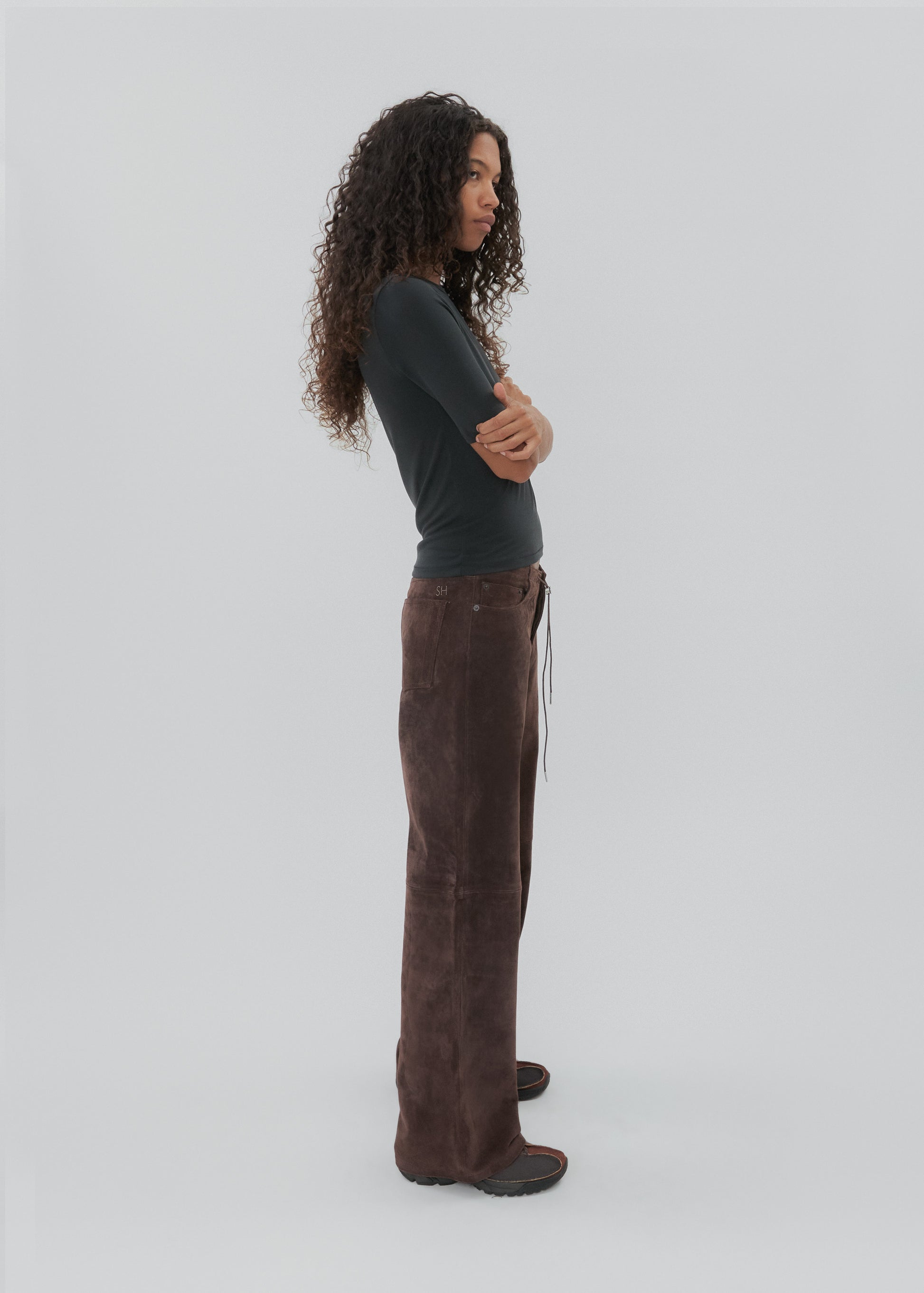 Person wearing a dark gray top and brown pants on a white background