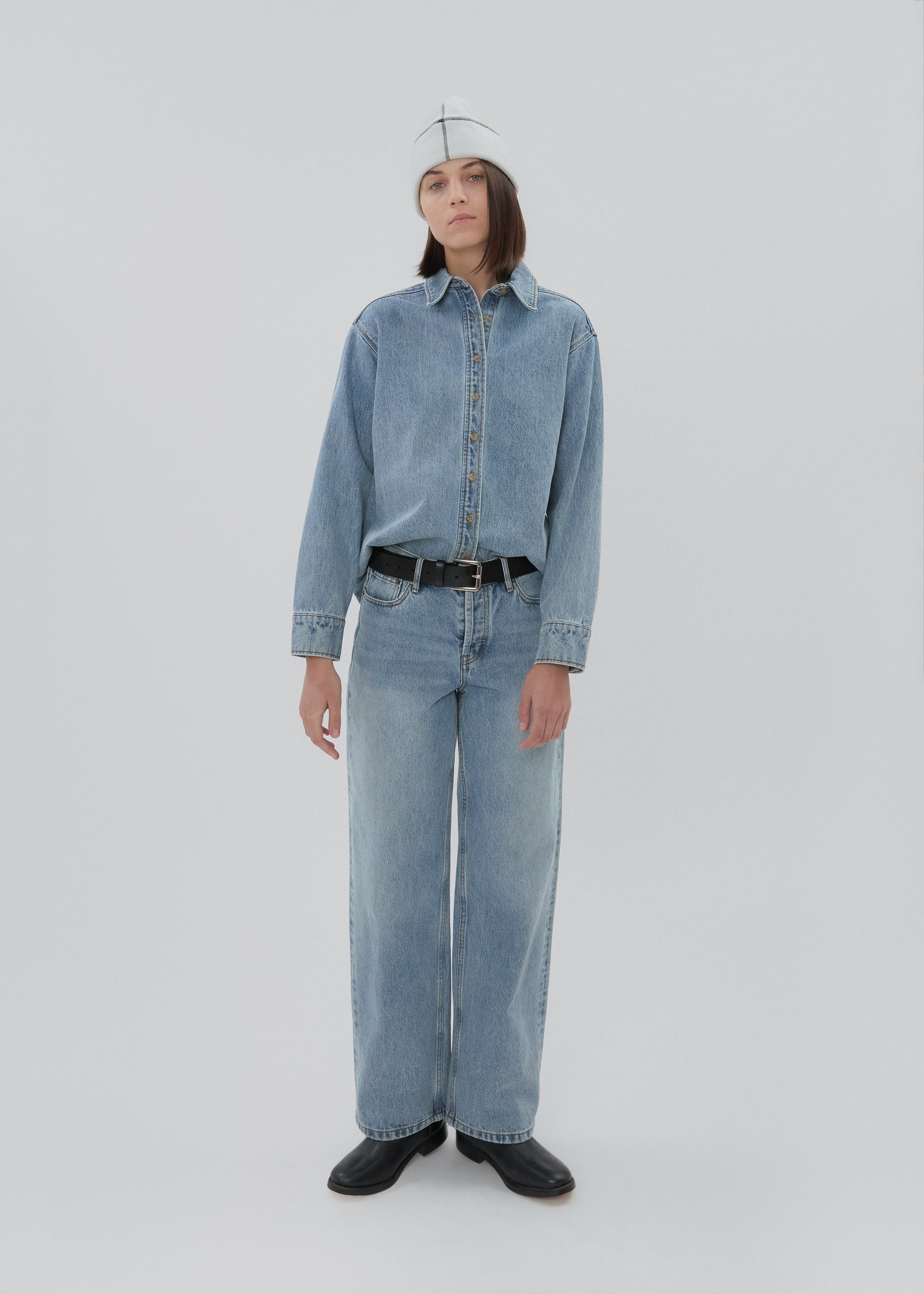 Person wearing a matching denim outfit on a plain background