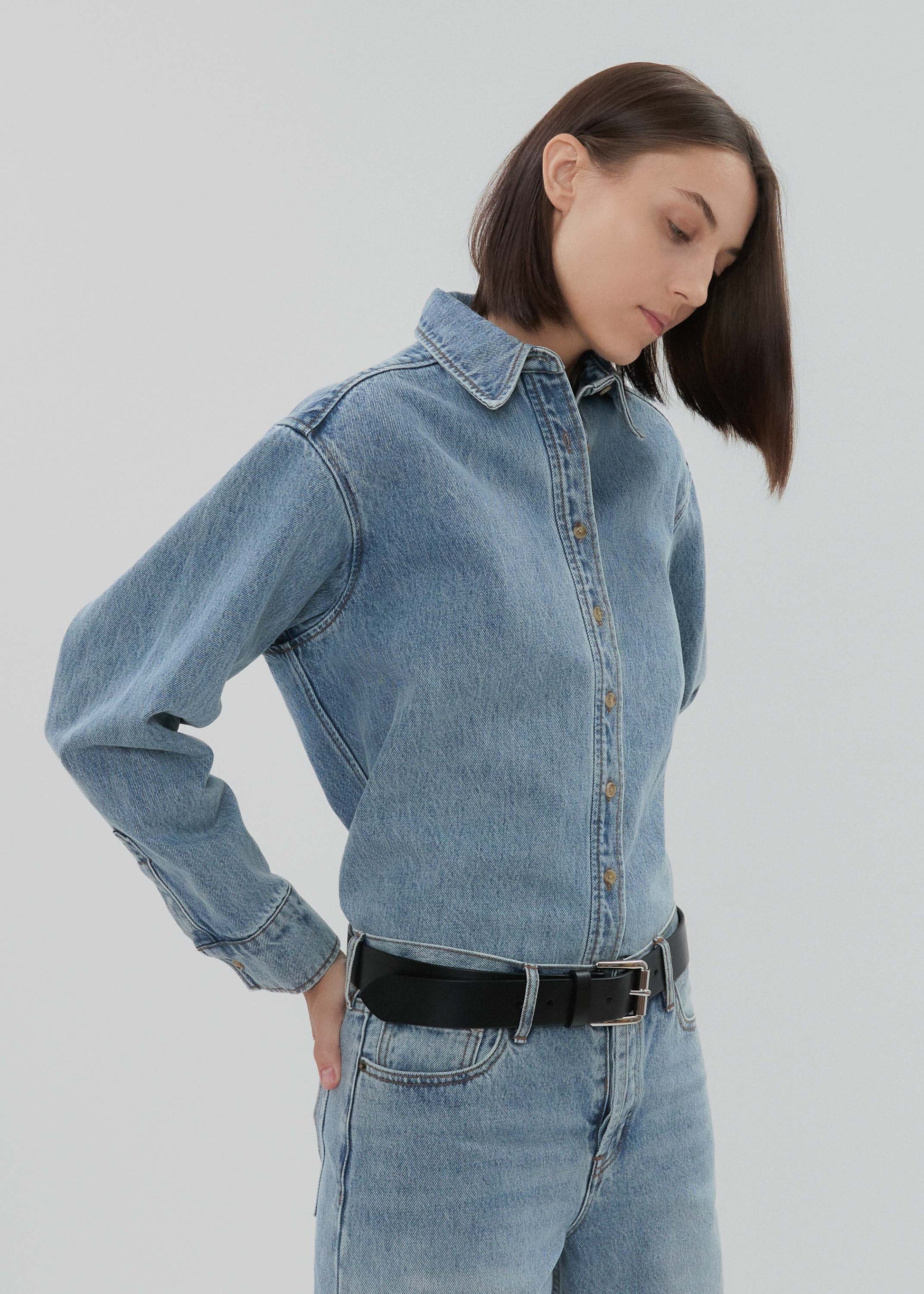 Person wearing a light blue denim outfit on a plain background