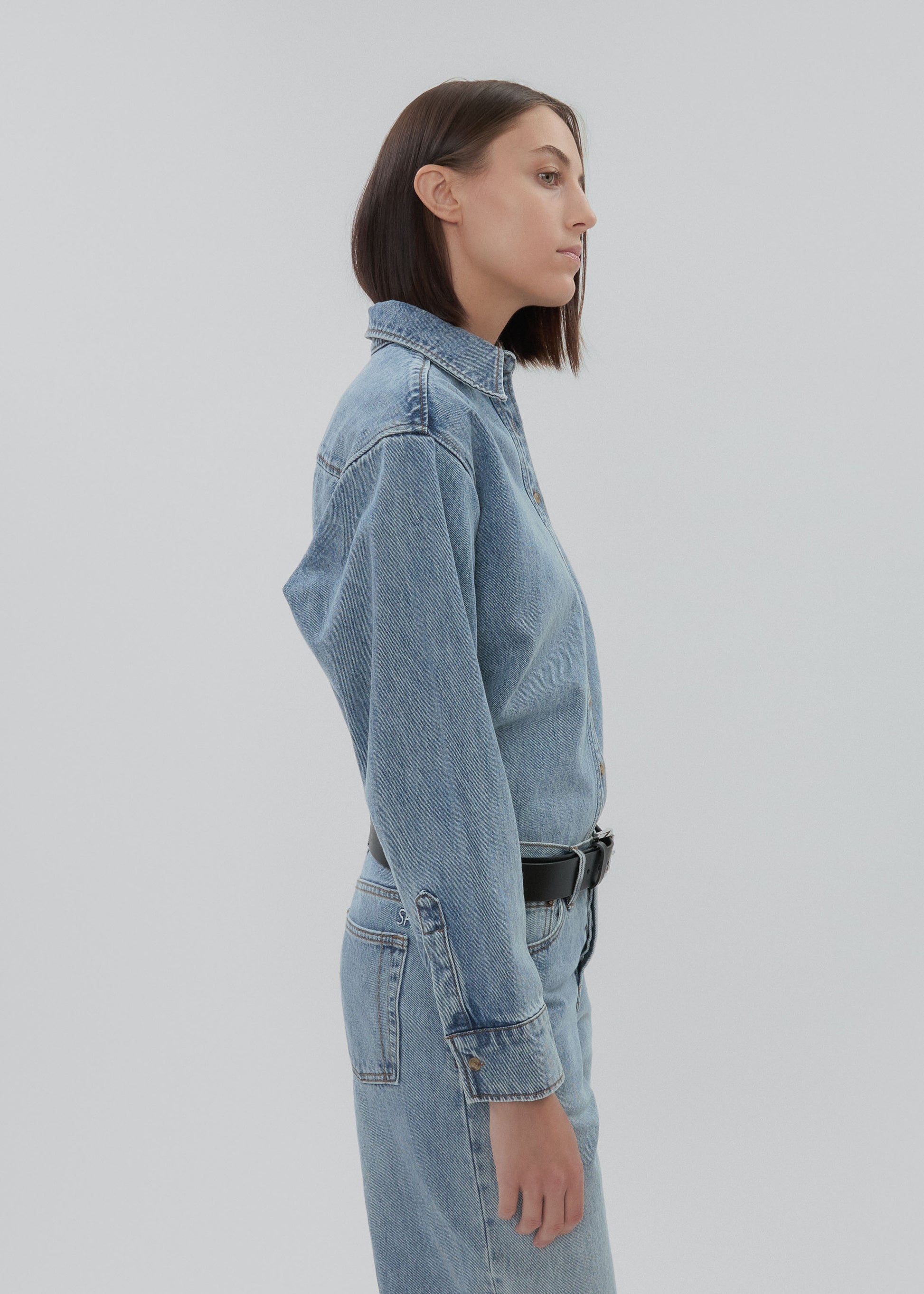 Person wearing a light blue denim outfit on a plain background