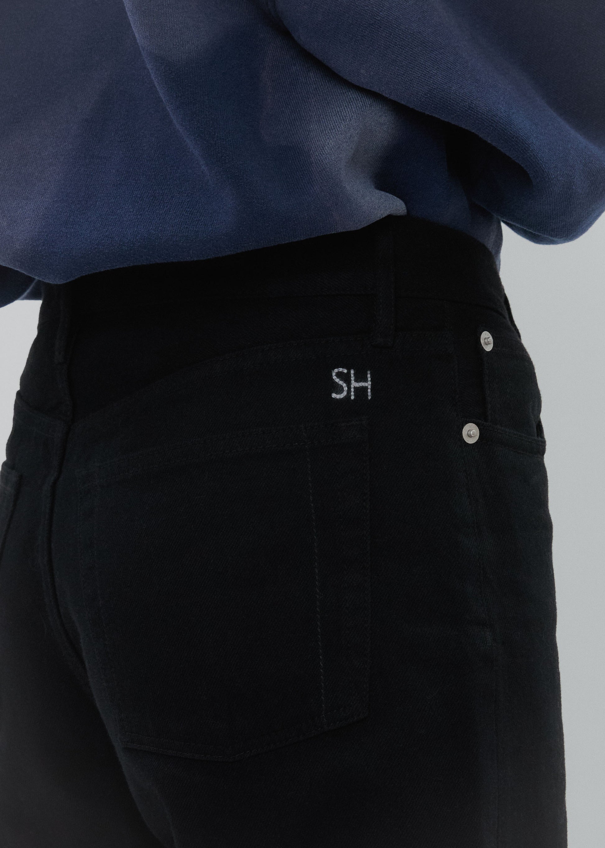 Black pants with 'SH' logo on pocket against a gray background